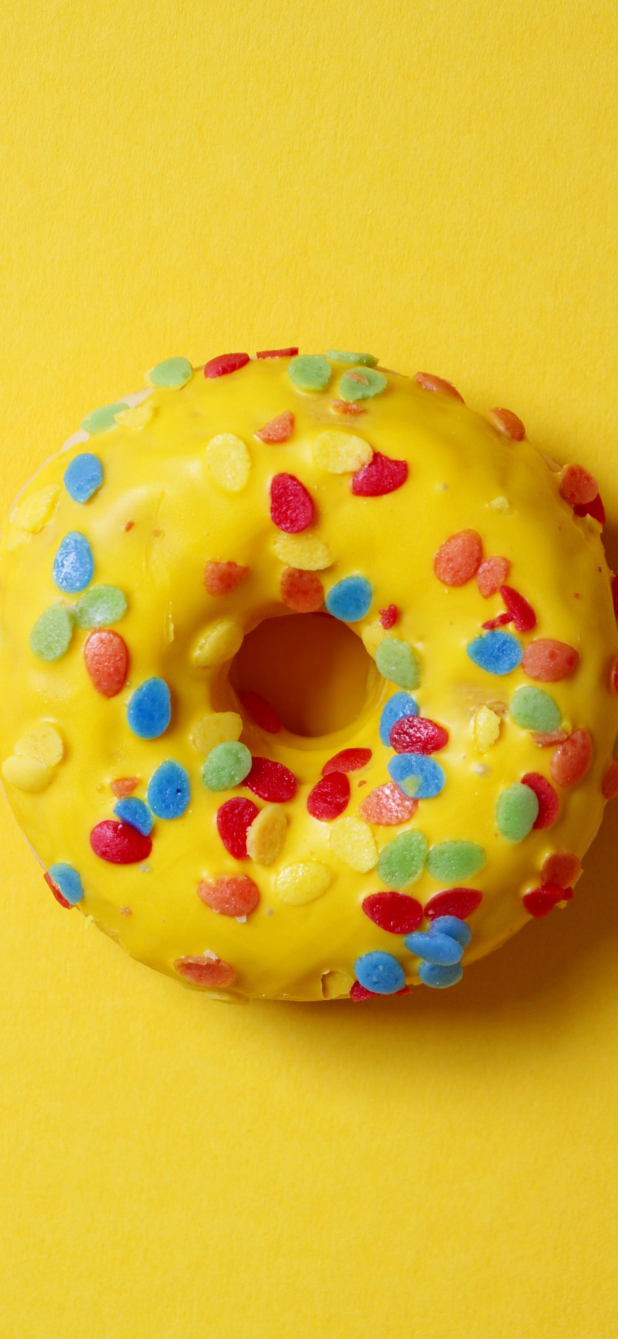 Doughnut With Sprinkles on Yellow Surface. Wallpaper in 1242x2688 Resolution