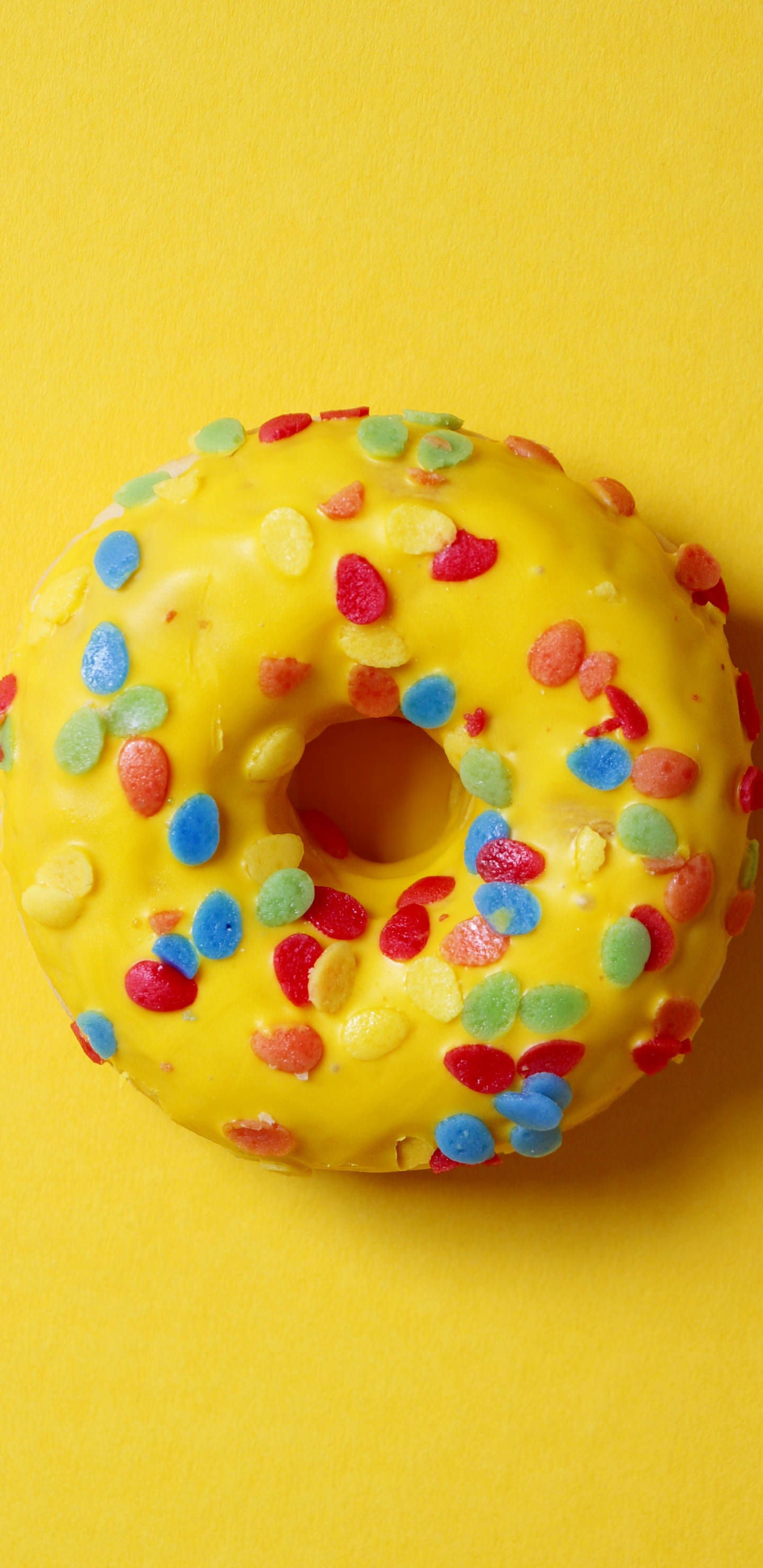 Doughnut With Sprinkles on Yellow Surface. Wallpaper in 1440x2960 Resolution