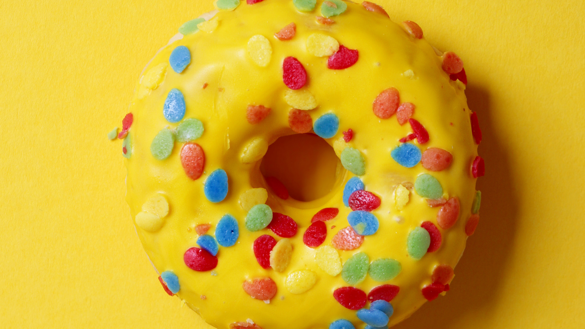 Doughnut With Sprinkles on Yellow Surface. Wallpaper in 1920x1080 Resolution