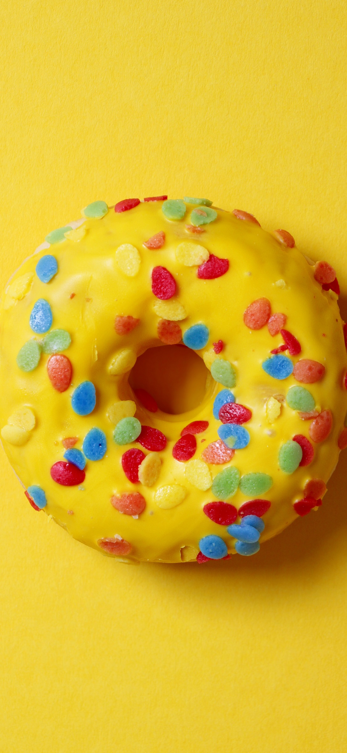 Donut Mit Streuseln Auf Gelber Oberfläche. Wallpaper in 1125x2436 Resolution