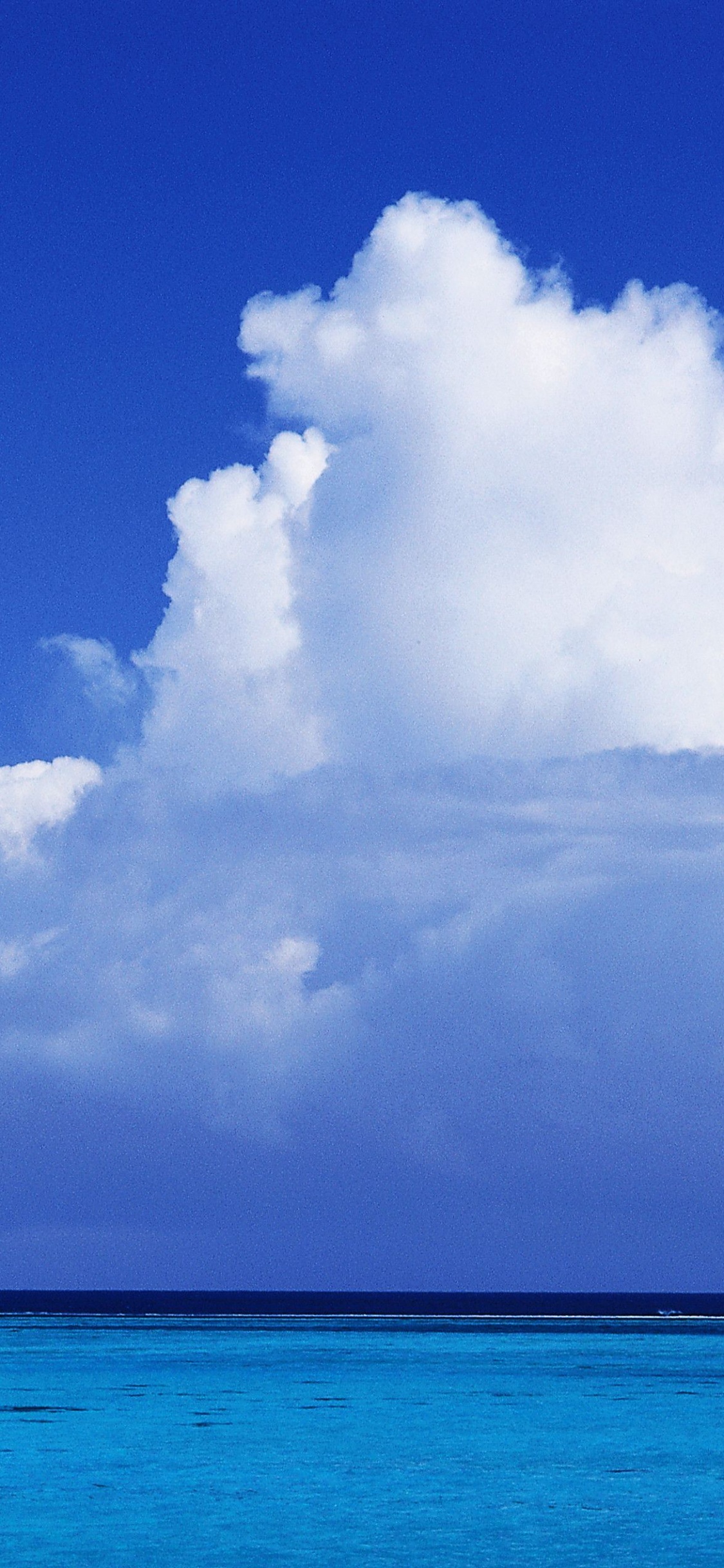 Blaues Meer Unter Blauem Himmel Und Weiße Wolken Tagsüber. Wallpaper in 1125x2436 Resolution