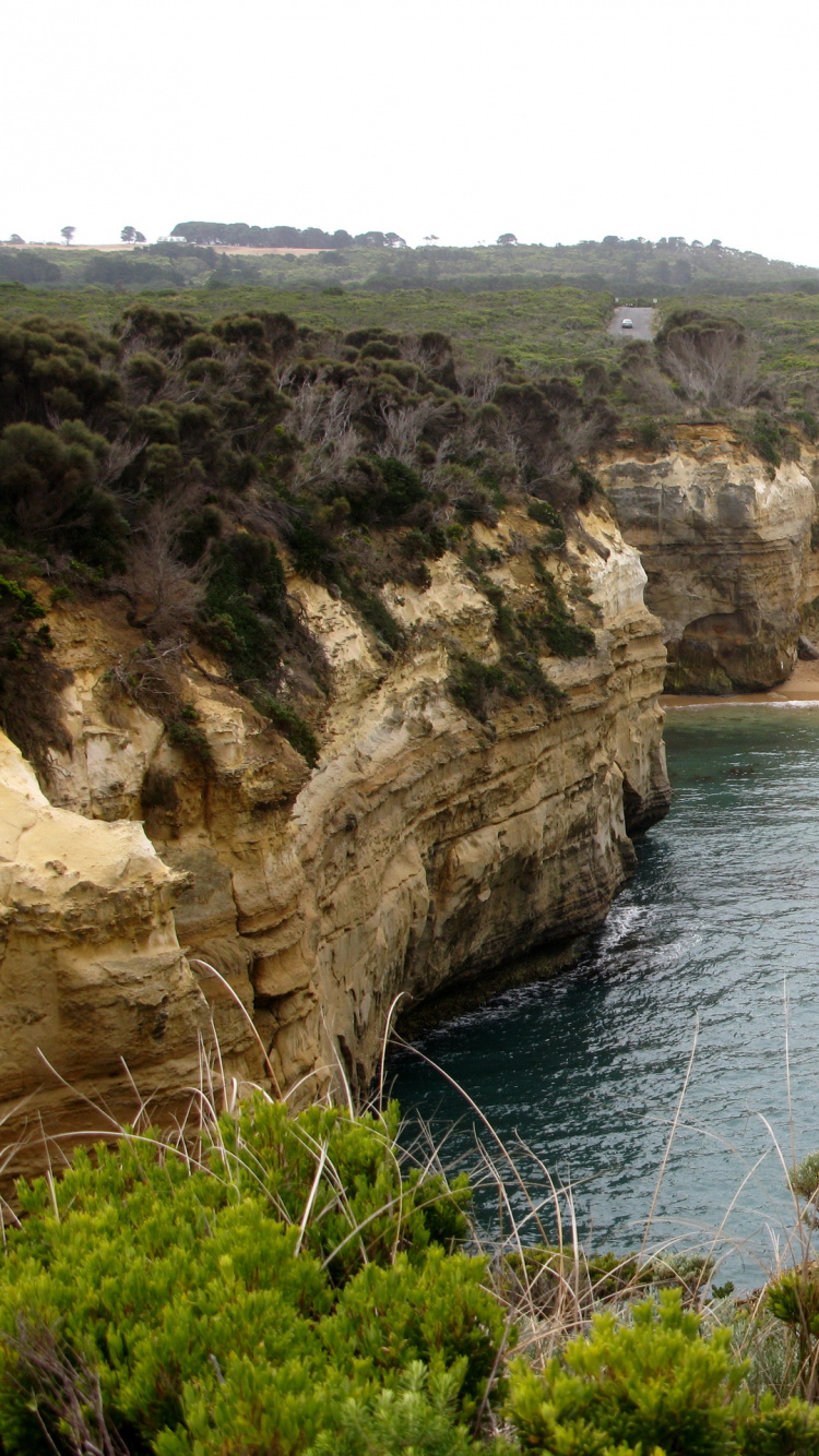 Brown Rock Formation Beside Body of Water During Daytime. Wallpaper in 750x1334 Resolution