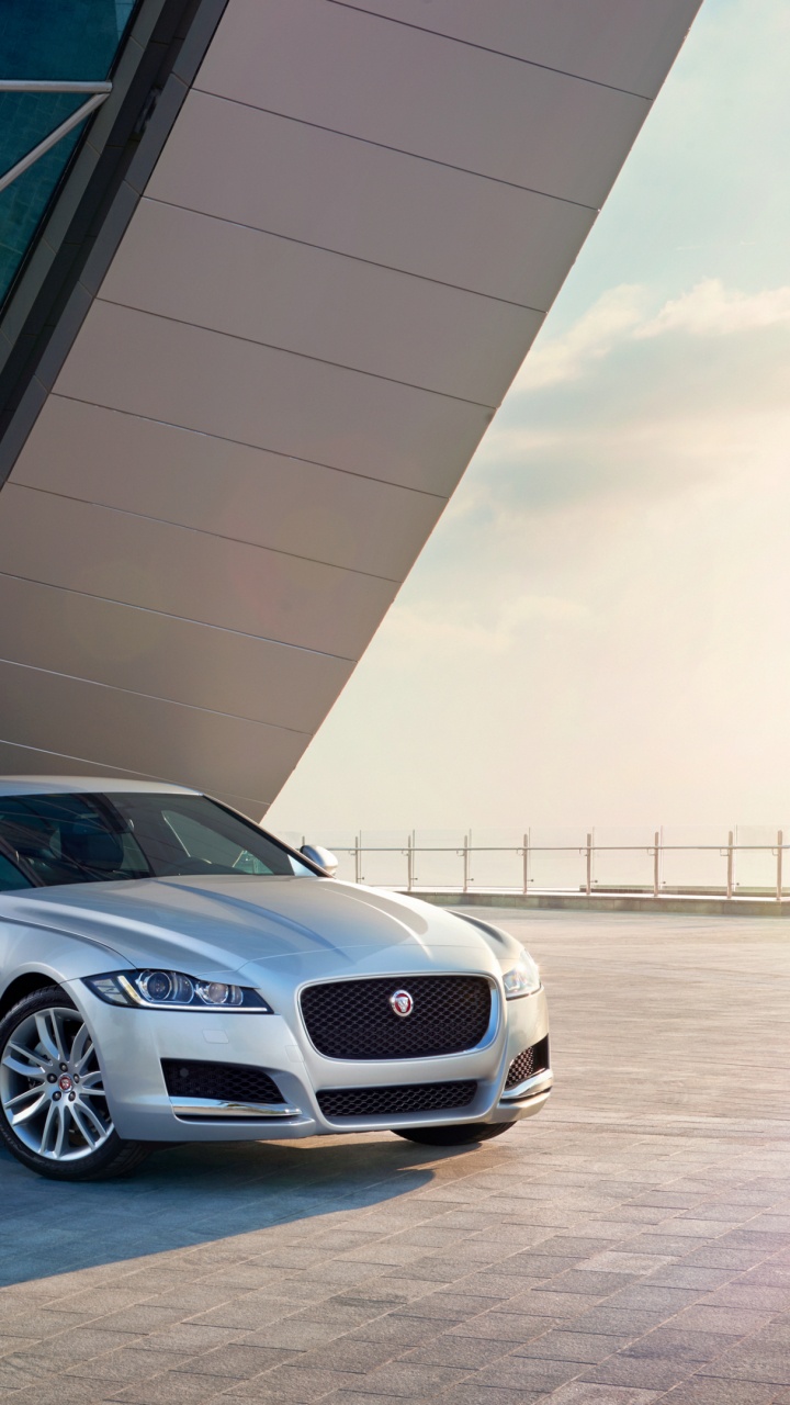 Silver Sedan Parked Beside White Building. Wallpaper in 720x1280 Resolution