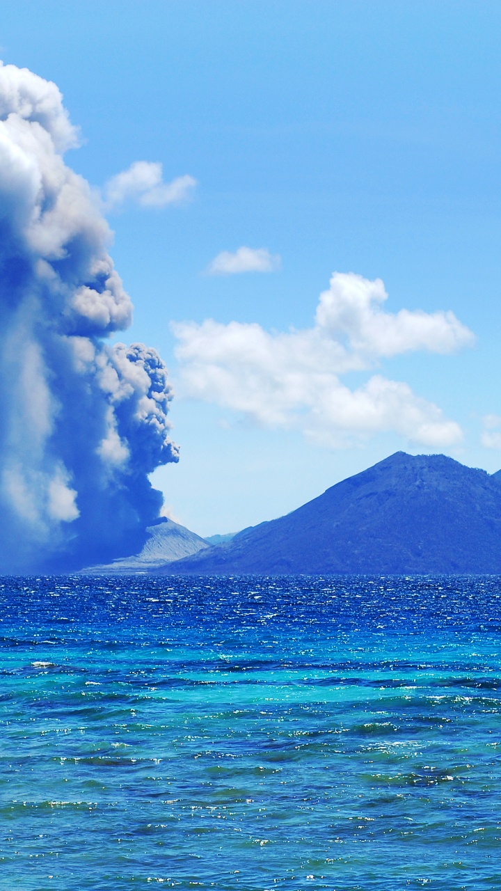 Mar Azul Cerca de la Montaña Bajo un Cielo Azul Durante el Día. Wallpaper in 720x1280 Resolution