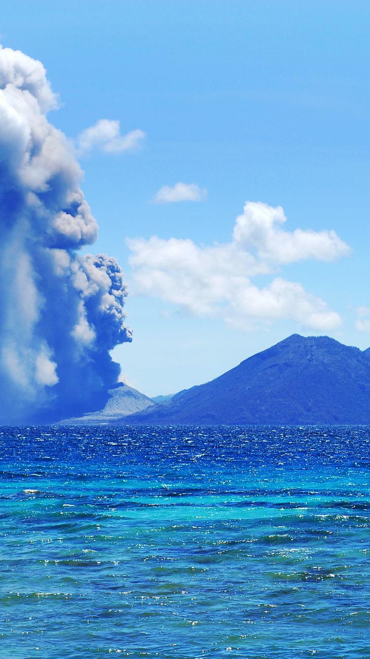 Mar Azul Cerca de la Montaña Bajo un Cielo Azul Durante el Día. Wallpaper in 750x1334 Resolution