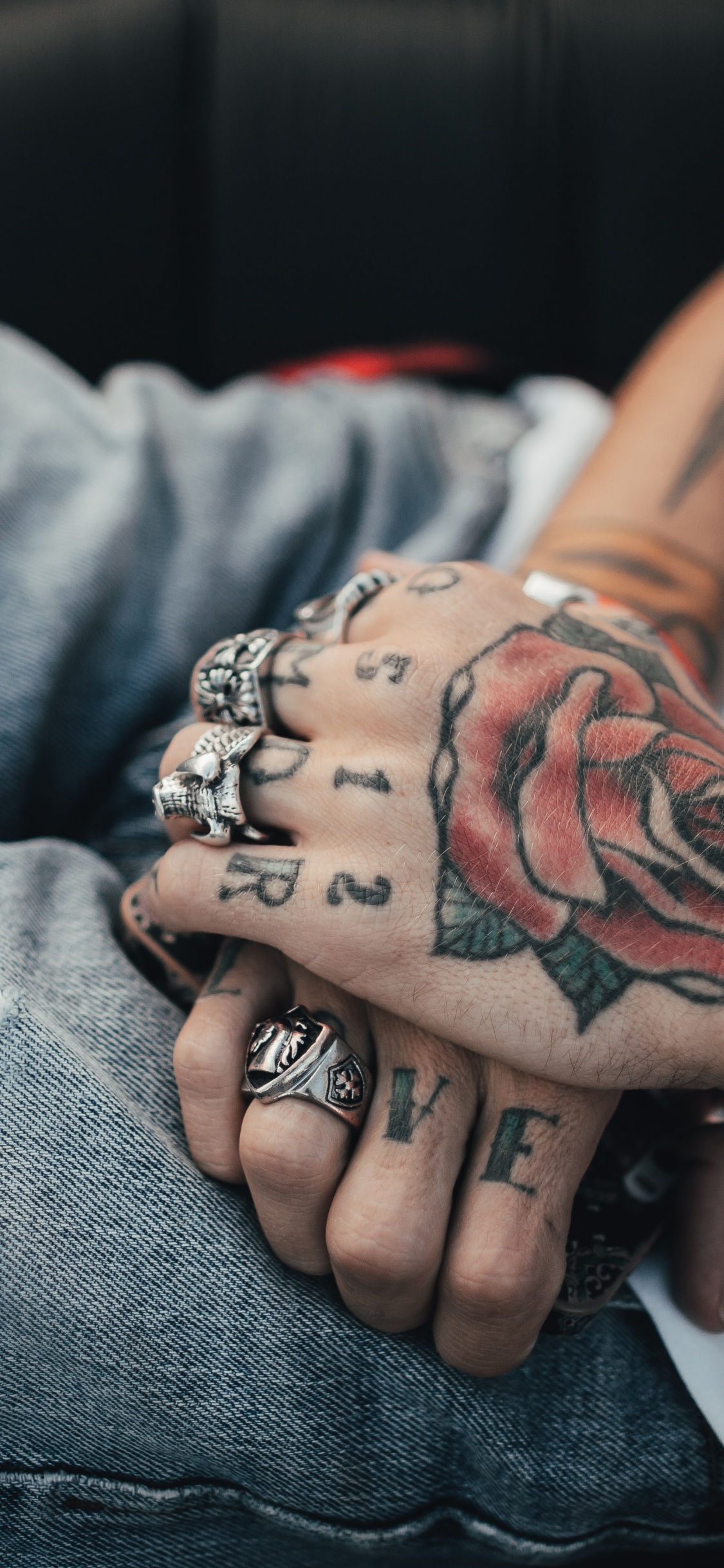 Person Mit Schwarzer Und Roter Rose Tattoo am Linken Arm. Wallpaper in 1125x2436 Resolution