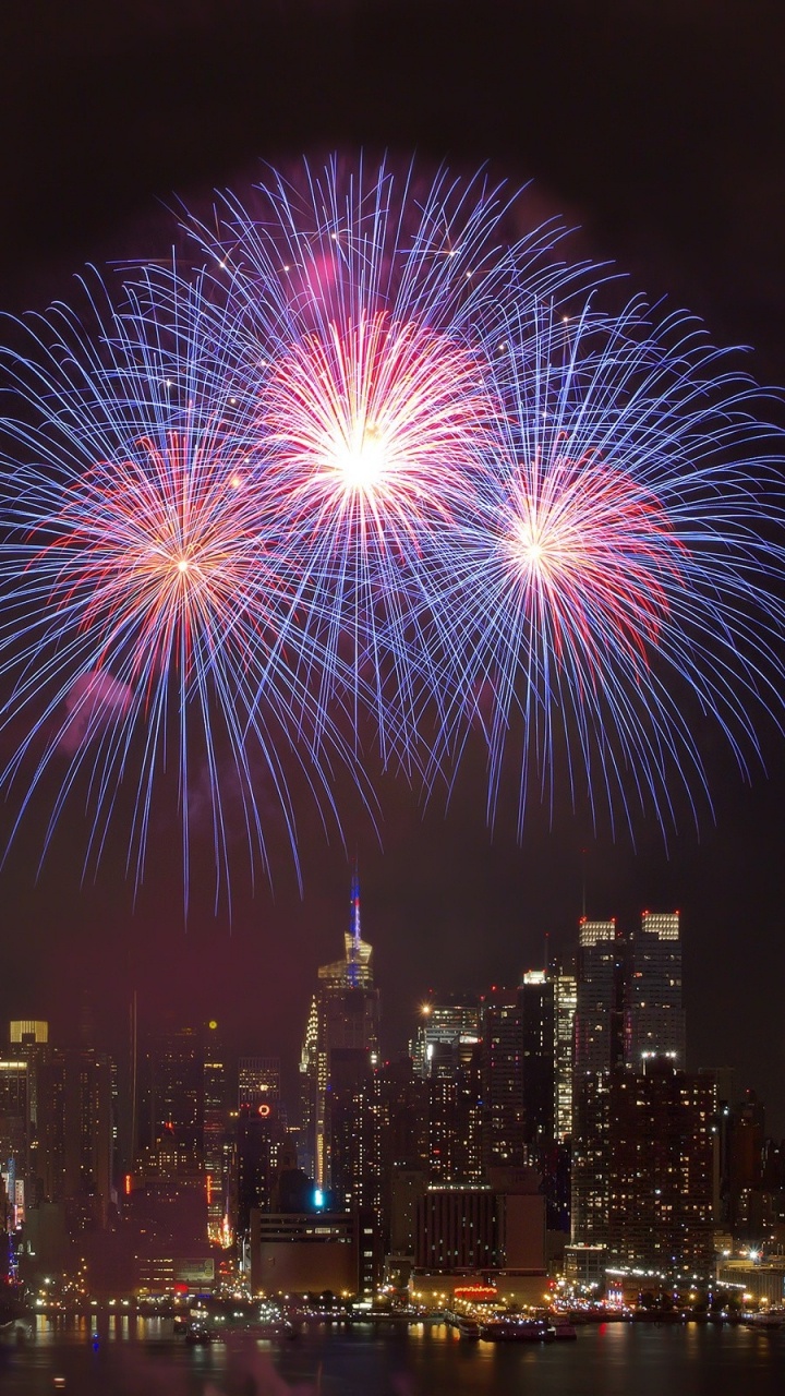 Fireworks Display Over City Buildings During Night Time. Wallpaper in 720x1280 Resolution