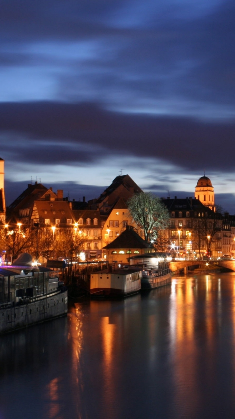 Braunes Betongebäude in Der Nähe Von Gewässern Während Der Nacht. Wallpaper in 750x1334 Resolution