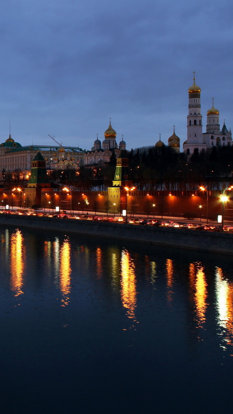 Skyline Der Stadt Über Gewässer Während Der Nacht. Wallpaper in 750x1334 Resolution