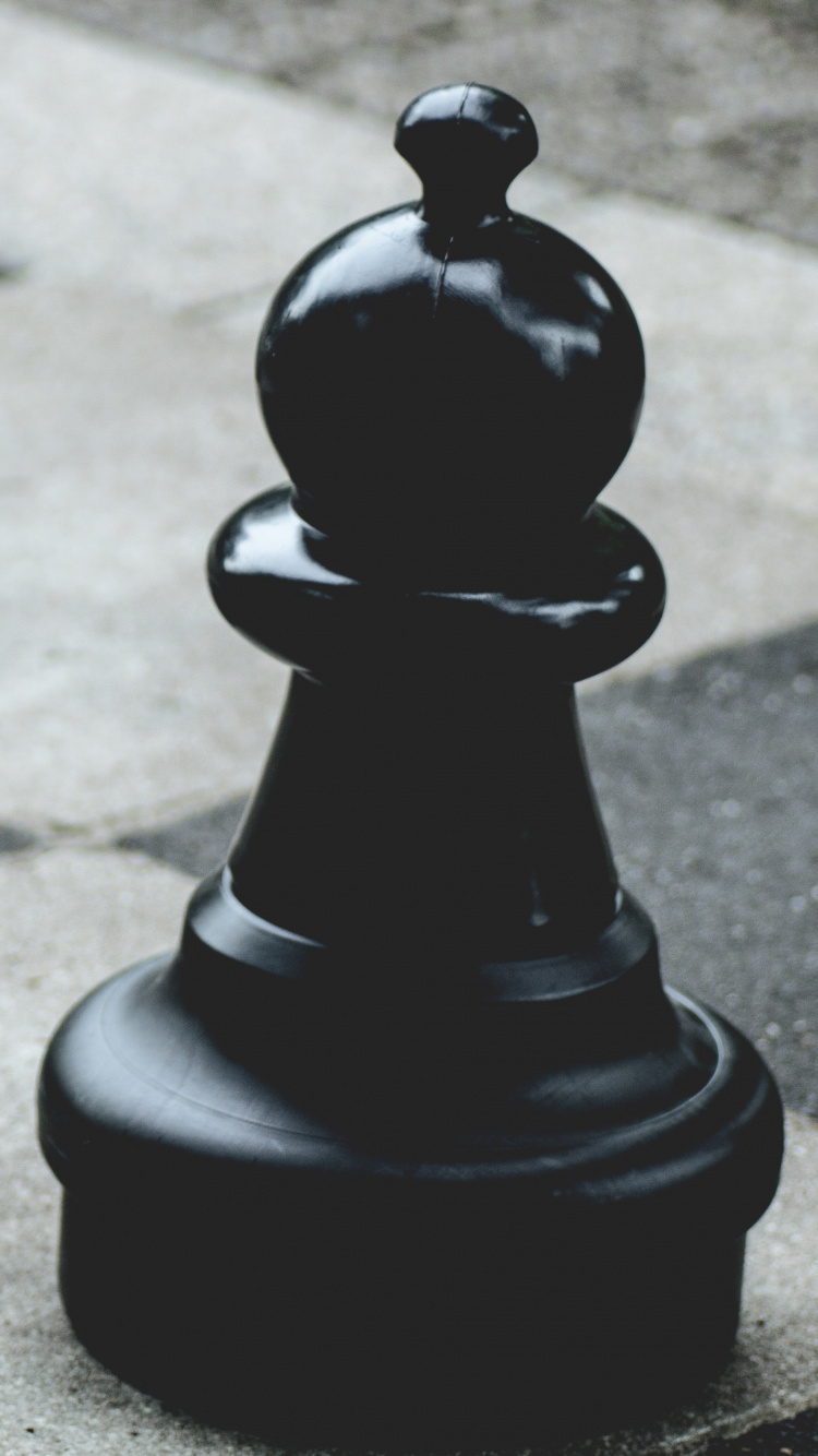 Pièce D'échecs Noire Sur la Chaussée en Béton Gris. Wallpaper in 750x1334 Resolution