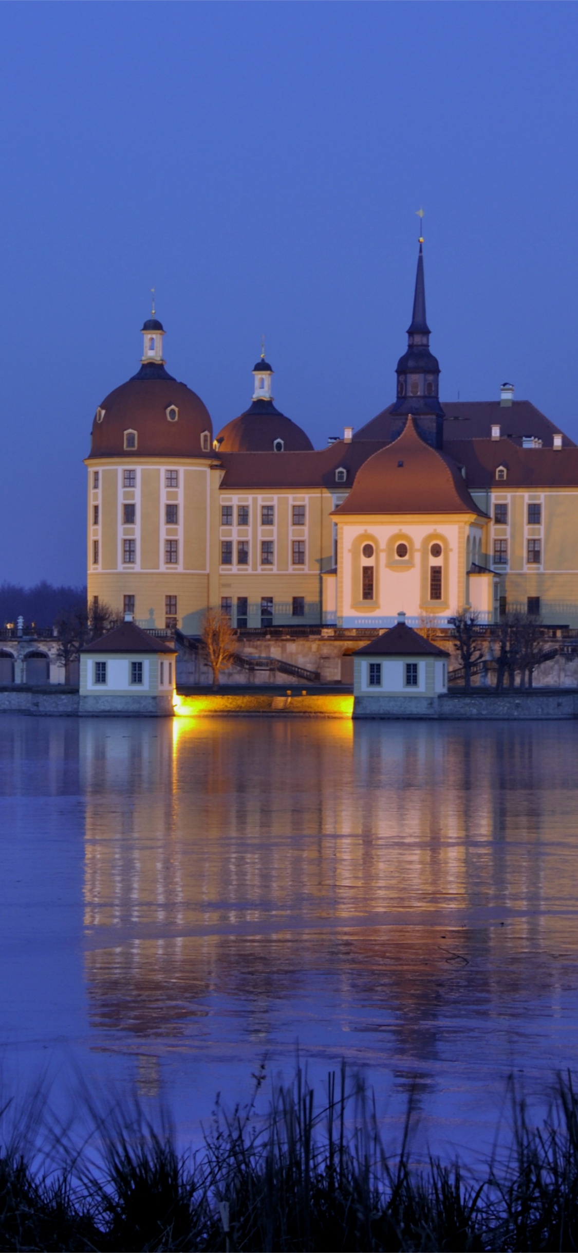 Brown Concrete Building Near Body of Water During Night Time. Wallpaper in 1125x2436 Resolution