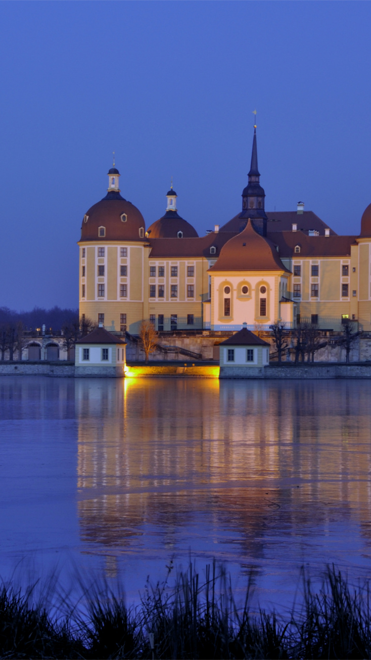 Brown Concrete Building Near Body of Water During Night Time. Wallpaper in 750x1334 Resolution
