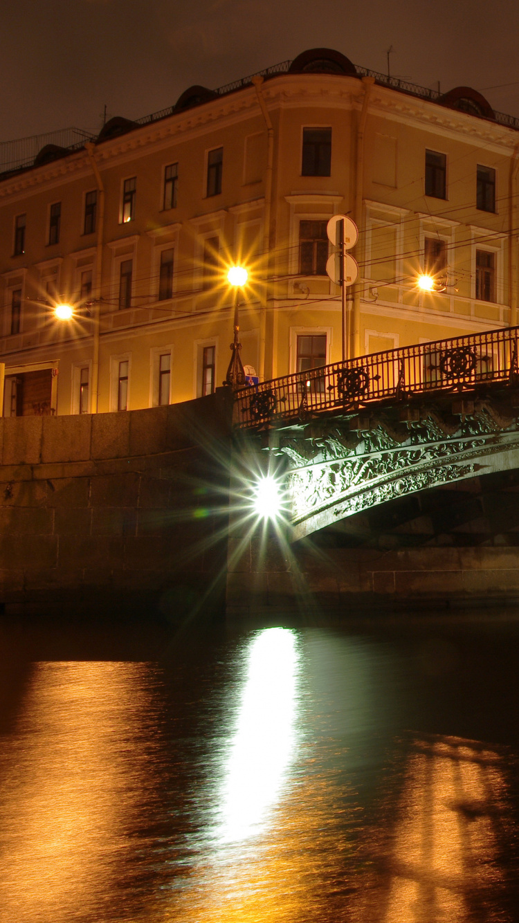 Brown Concrete Building Near Bridge During Night Time. Wallpaper in 750x1334 Resolution