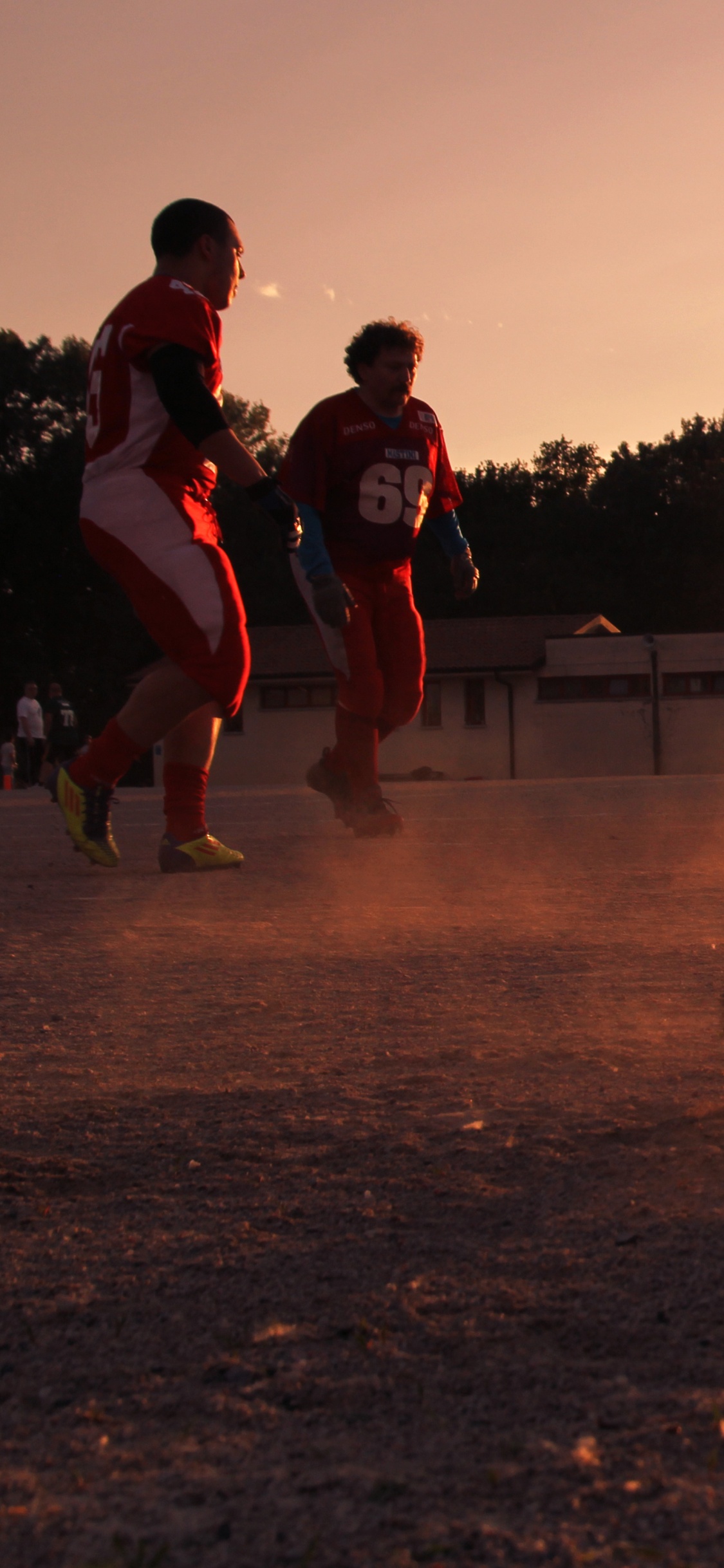 Gente Saltando en el Campo Marrón Durante el Día. Wallpaper in 1125x2436 Resolution
