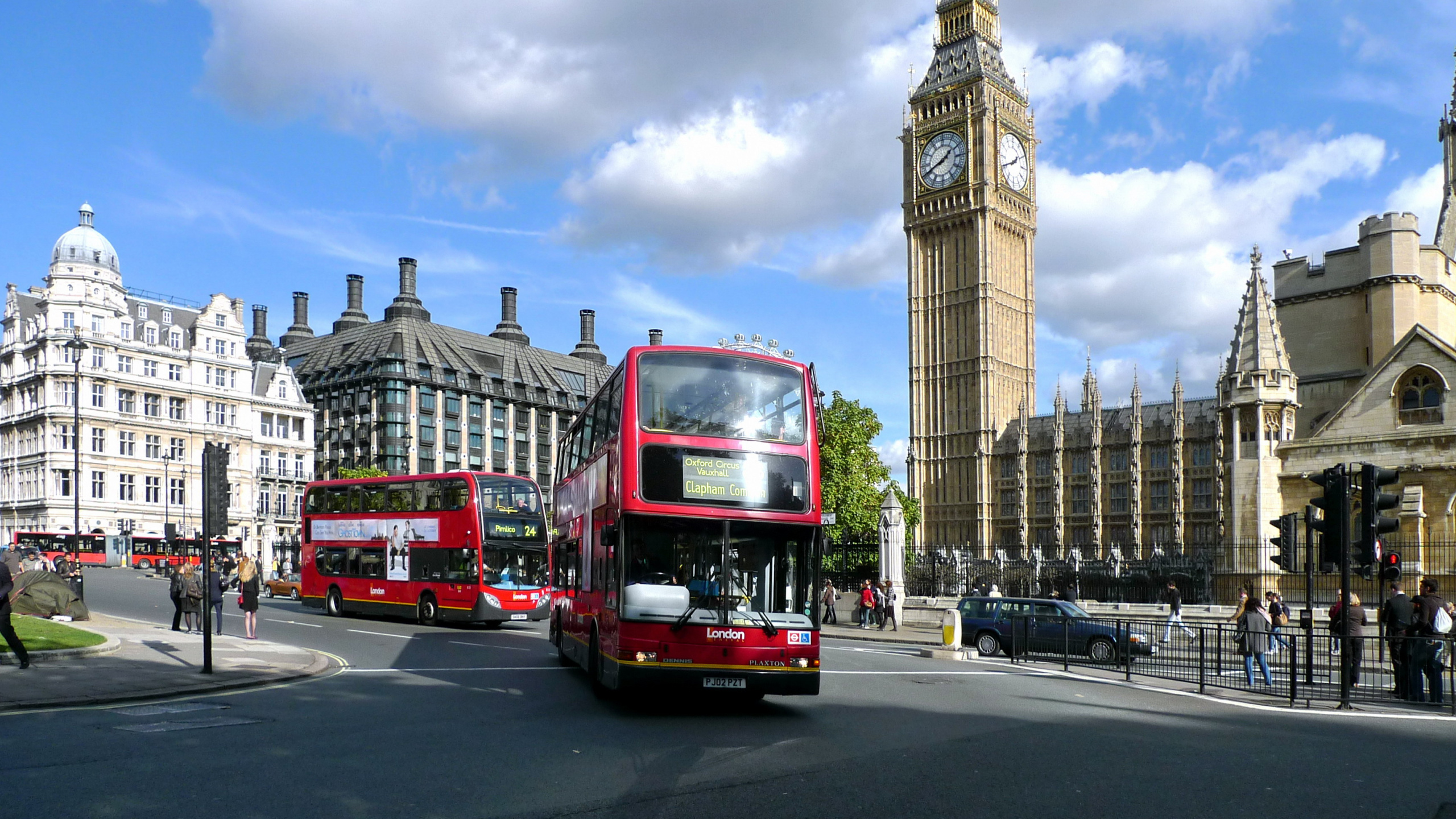 Red Double Decker Bus on Road Near Brown Concrete Building During Daytime. Wallpaper in 2560x1440 Resolution
