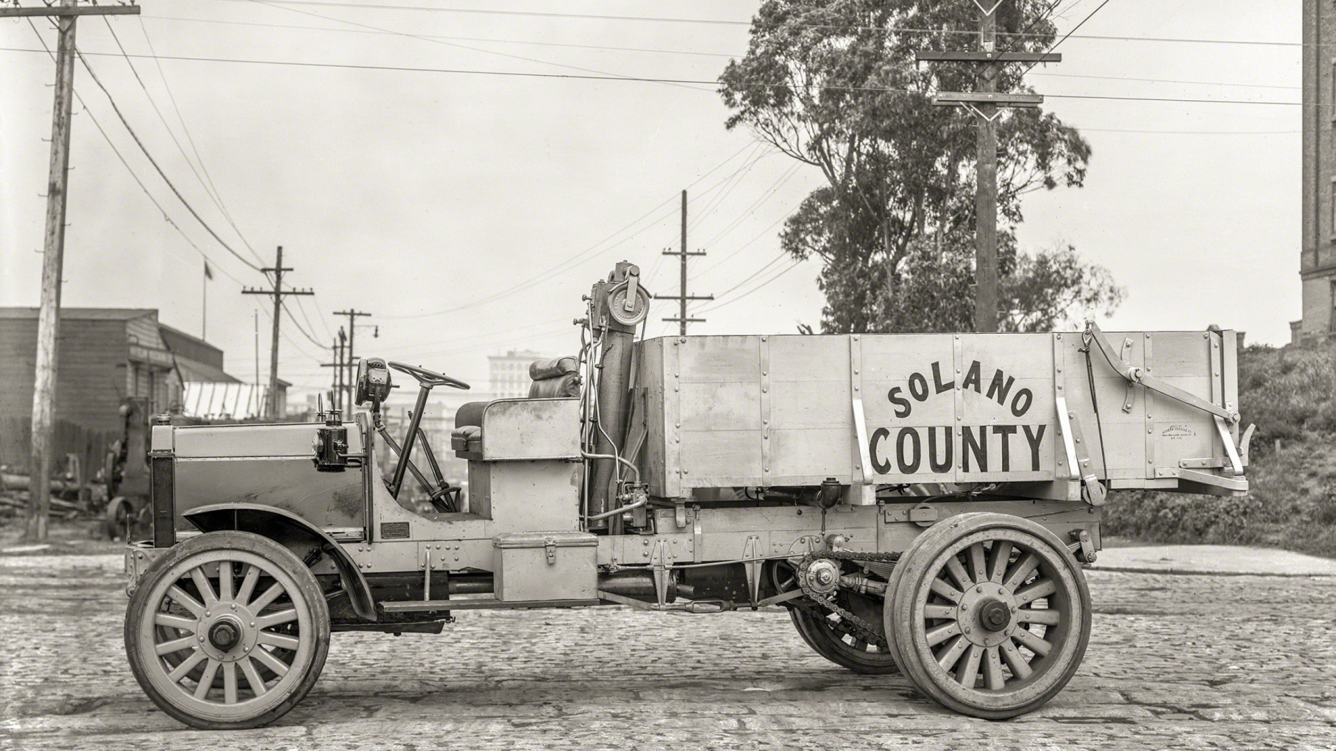 Grayscale Photo of a Trailer Truck Parked Near Trees. Wallpaper in 1920x1080 Resolution