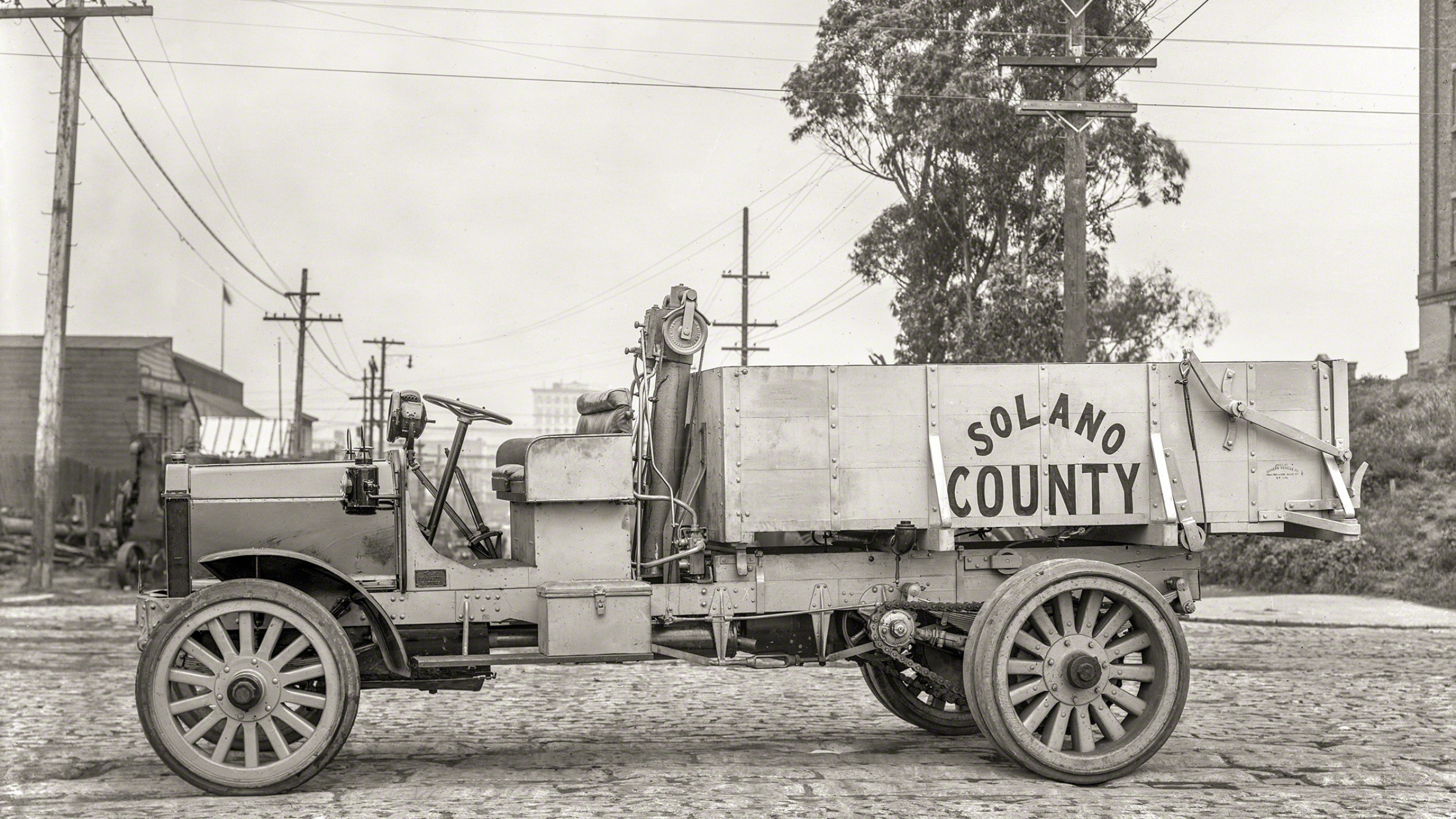 Grayscale Photo of a Trailer Truck Parked Near Trees. Wallpaper in 2560x1440 Resolution