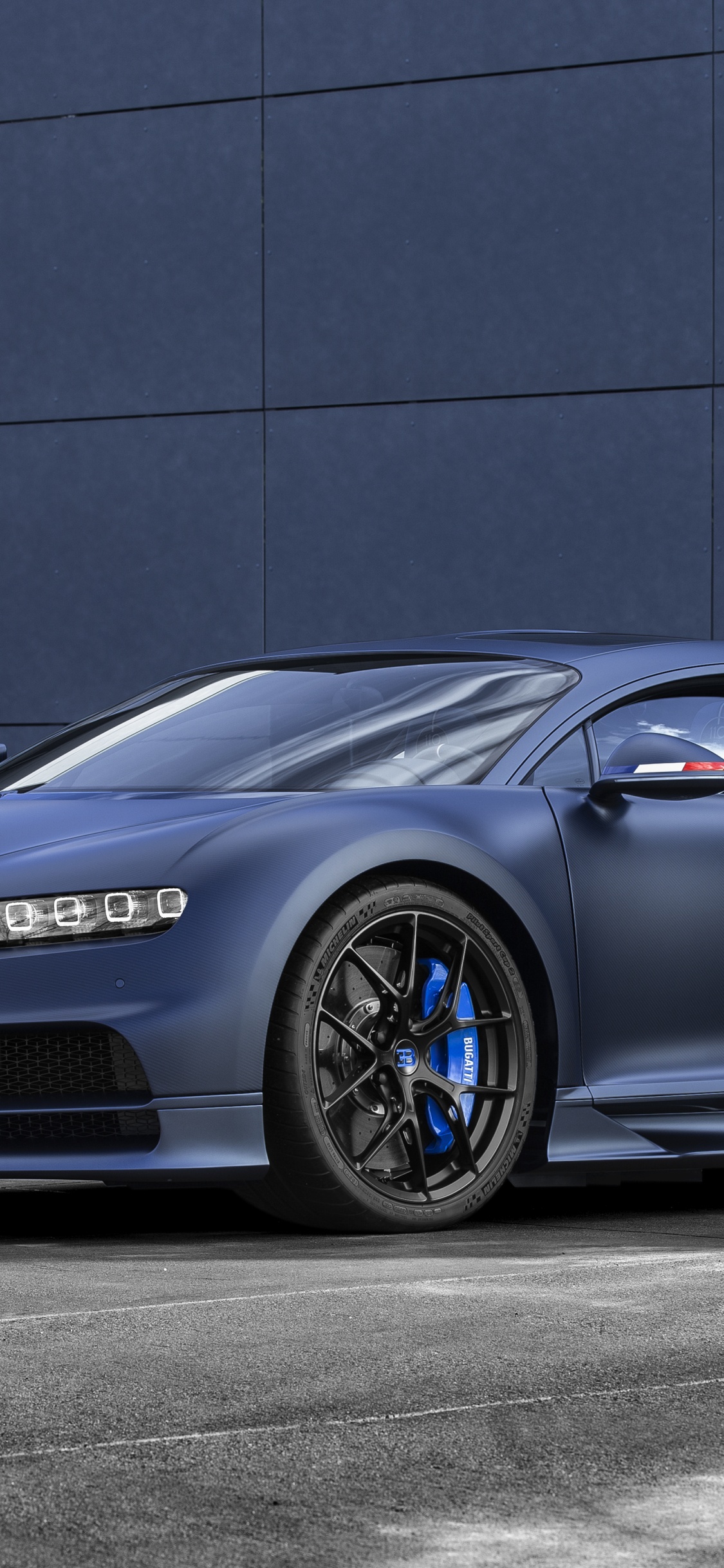 Blue Porsche 911 Parked Near Grey Concrete Building During Daytime. Wallpaper in 1125x2436 Resolution