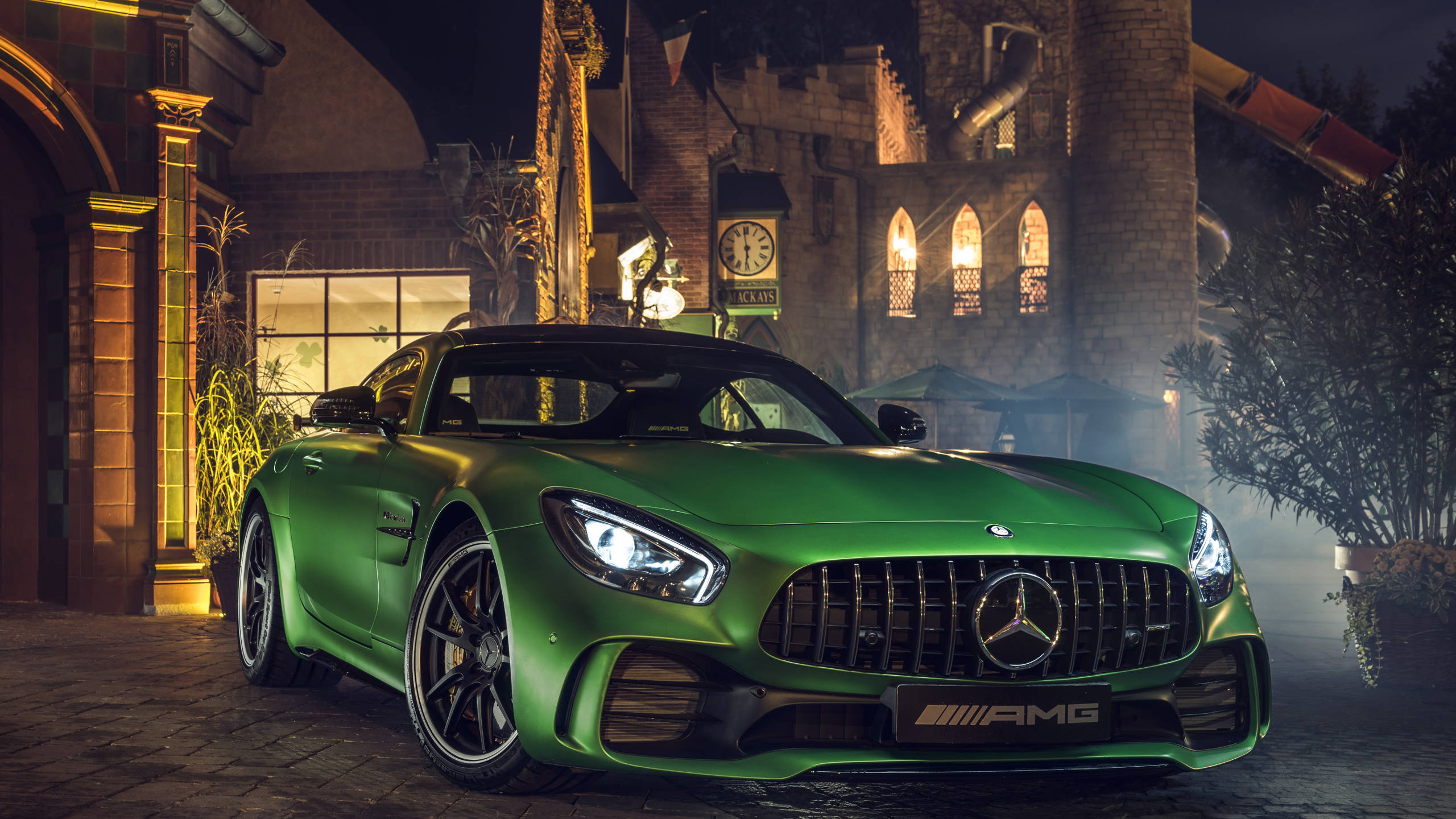 Green Car Parked Beside Brown Brick Building. Wallpaper in 2560x1440 Resolution