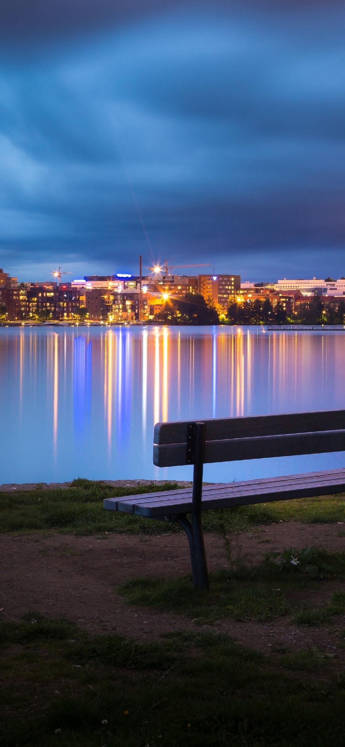 City Skyline Across Body of Water During Night Time. Wallpaper in 1125x2436 Resolution
