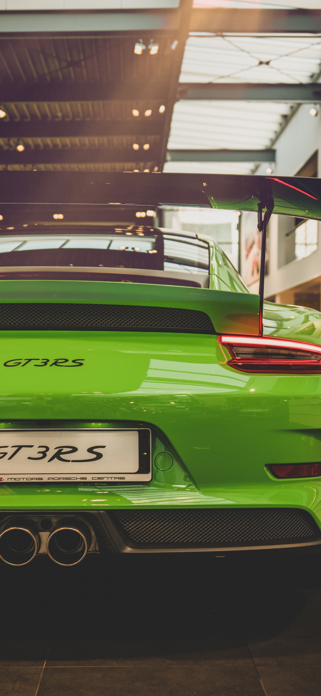 Green Porsche 911 Parked in Front of Building. Wallpaper in 1125x2436 Resolution