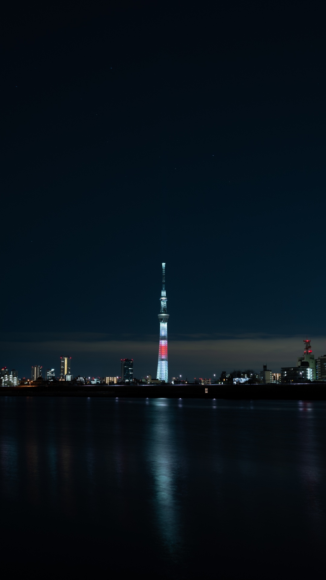 White and Red Tower Near Body of Water During Night Time. Wallpaper in 1080x1920 Resolution