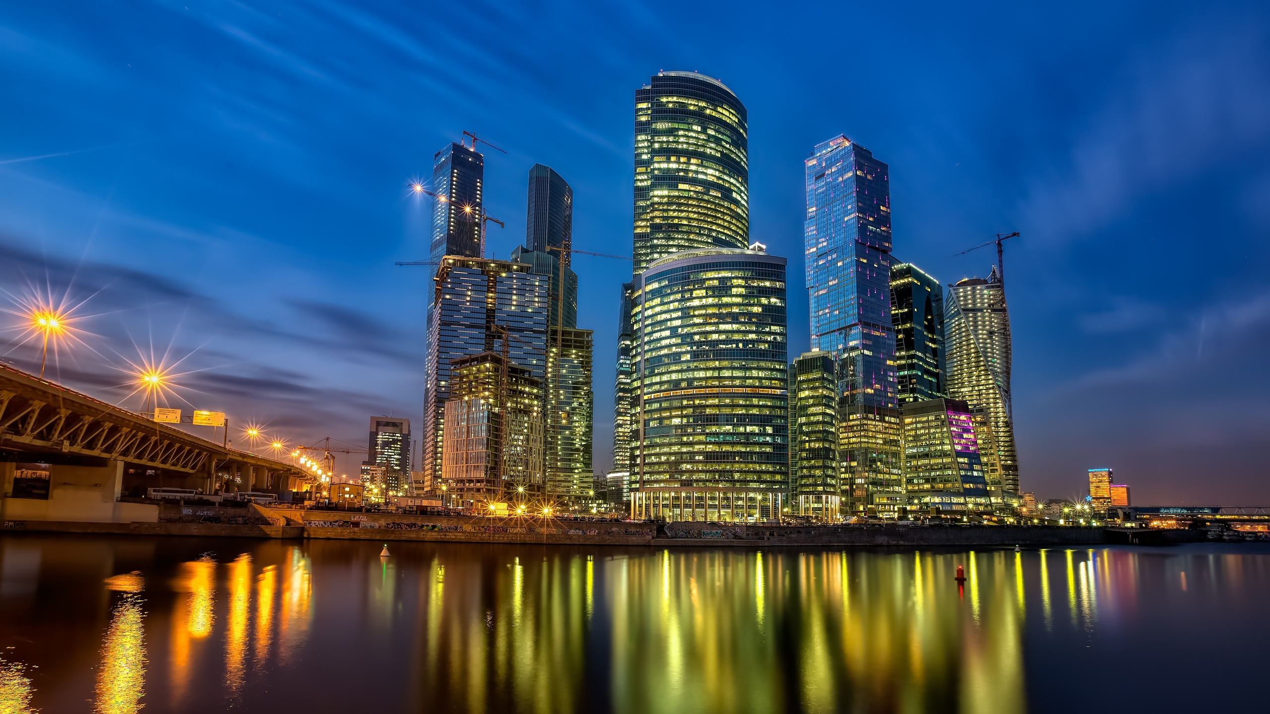 Skyline Der Stadt Über Gewässer Während Der Nacht. Wallpaper in 2560x1440 Resolution