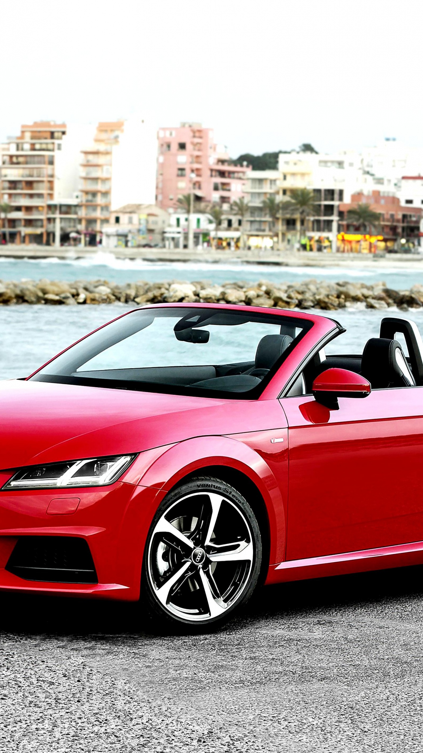 Red Convertible Car Parked Near Body of Water During Daytime. Wallpaper in 1440x2560 Resolution