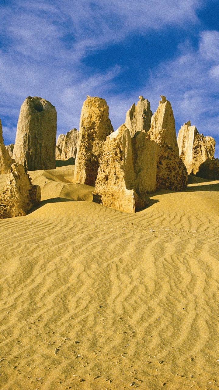 Braune Felsformation Auf Braunem Sand Unter Blauem Himmel Tagsüber. Wallpaper in 720x1280 Resolution