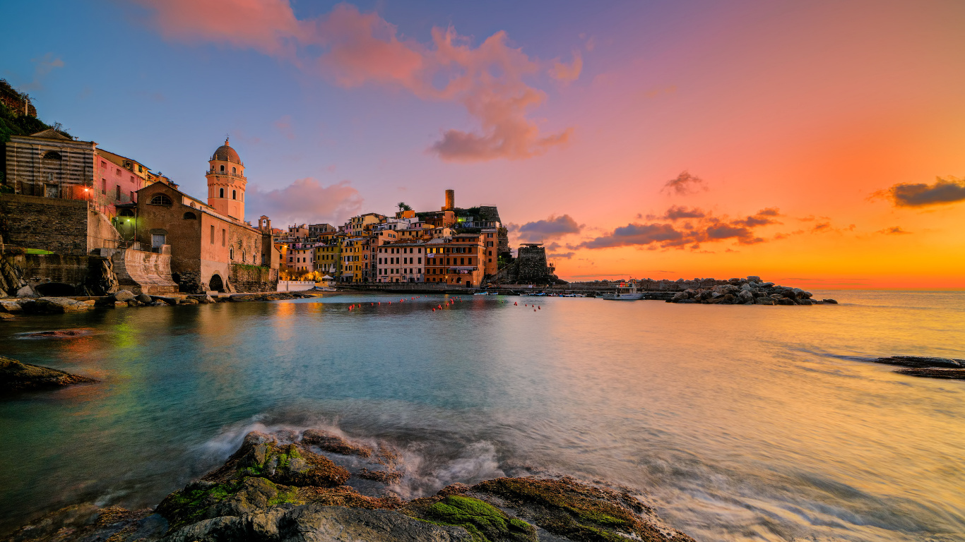 Brown Concrete Building Near Body of Water During Sunset. Wallpaper in 1366x768 Resolution