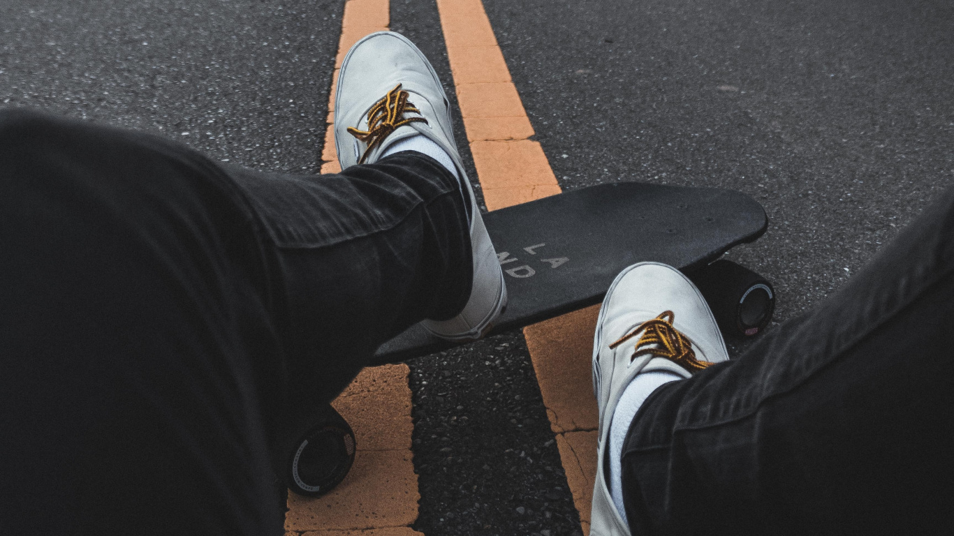 Persona en Pantalones Negros y Zapatillas Blancas Sentado en la Carretera de Hormigón Gris Durante el Día. Wallpaper in 1366x768 Resolution