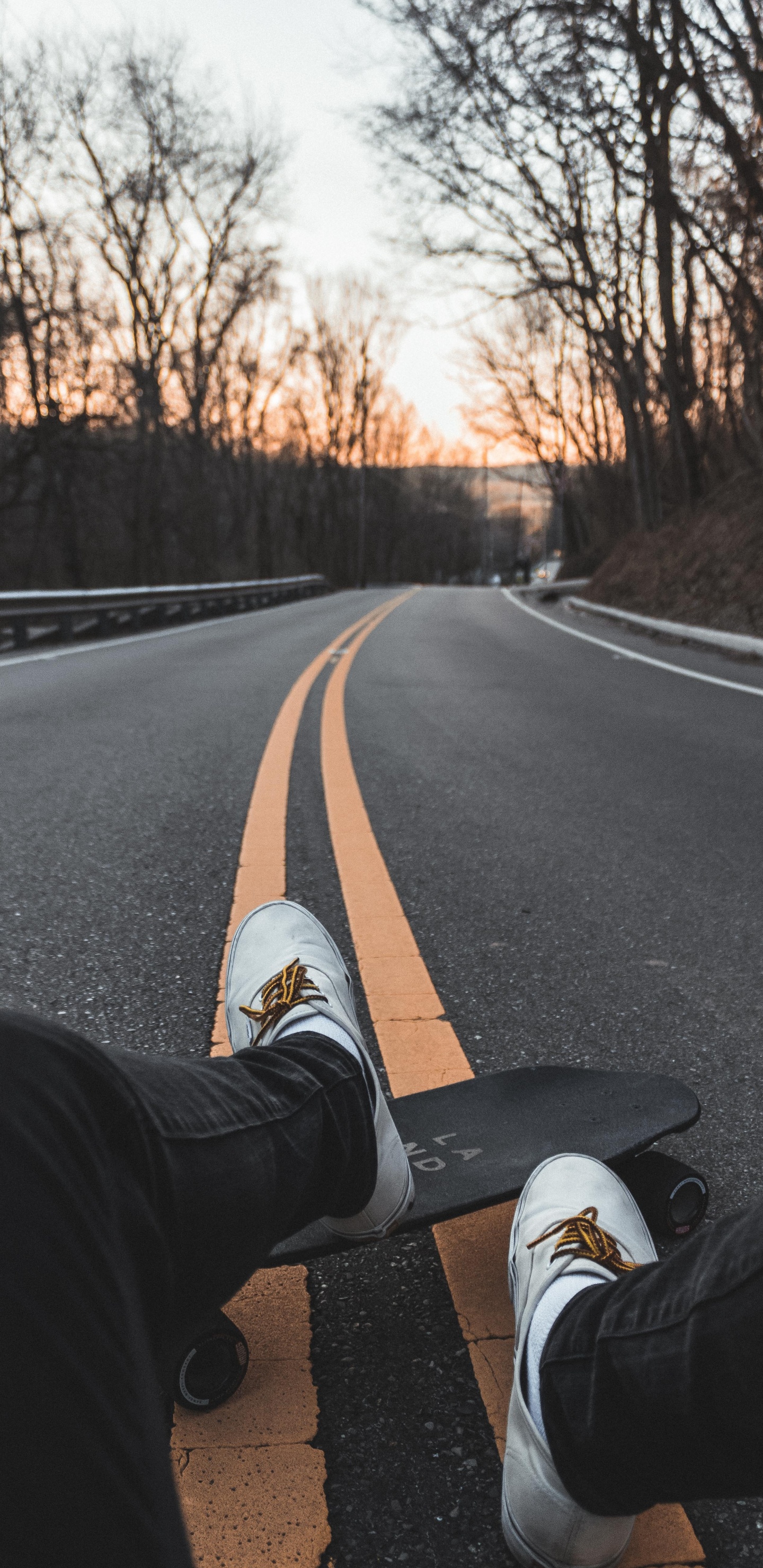 Personne en Pantalon Noir et Baskets Blanches Assise Sur Une Route en Béton Gris Pendant la Journée. Wallpaper in 1440x2960 Resolution