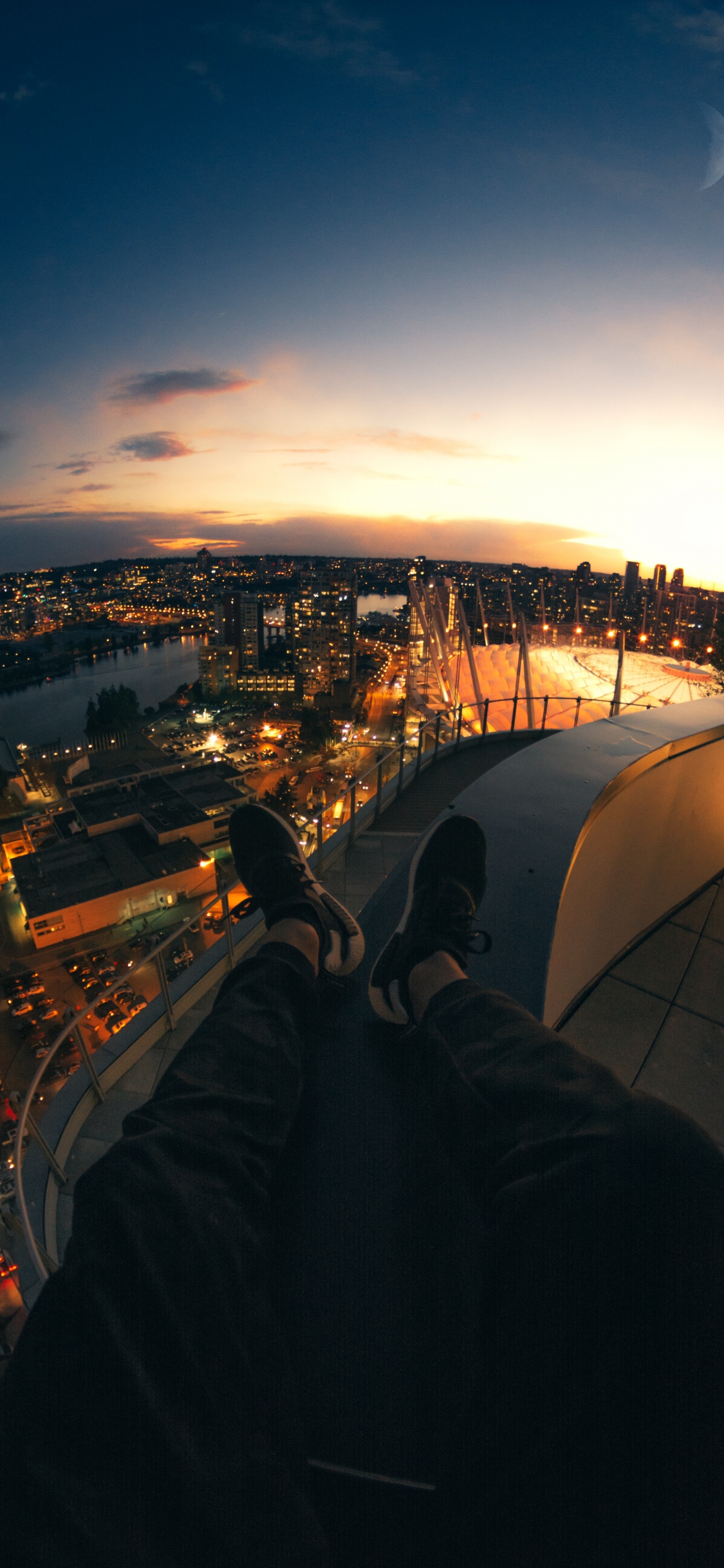 Personne en Pantalon Noir Assis Sur le Toit Pendant la Nuit. Wallpaper in 1125x2436 Resolution