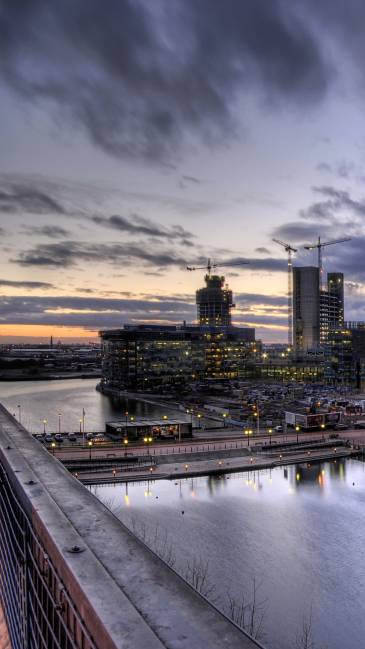 Skyline Der Stadt Über Gewässer Während Der Nacht. Wallpaper in 750x1334 Resolution