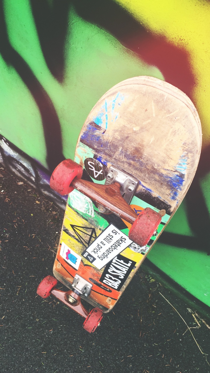 Skateboard Rouge et Jaune Sur Mur Vert. Wallpaper in 720x1280 Resolution