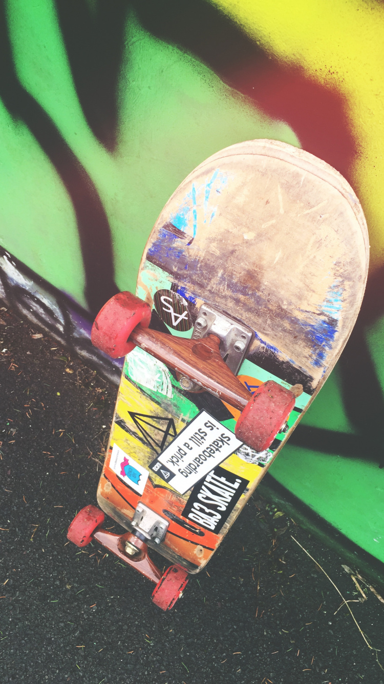 Skateboard Rouge et Jaune Sur Mur Vert. Wallpaper in 750x1334 Resolution