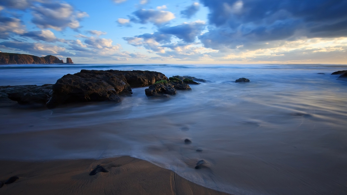 Brown Rock Formation on Sea Shore Under Blue Sky and White Clouds During Daytime. Wallpaper in 1366x768 Resolution