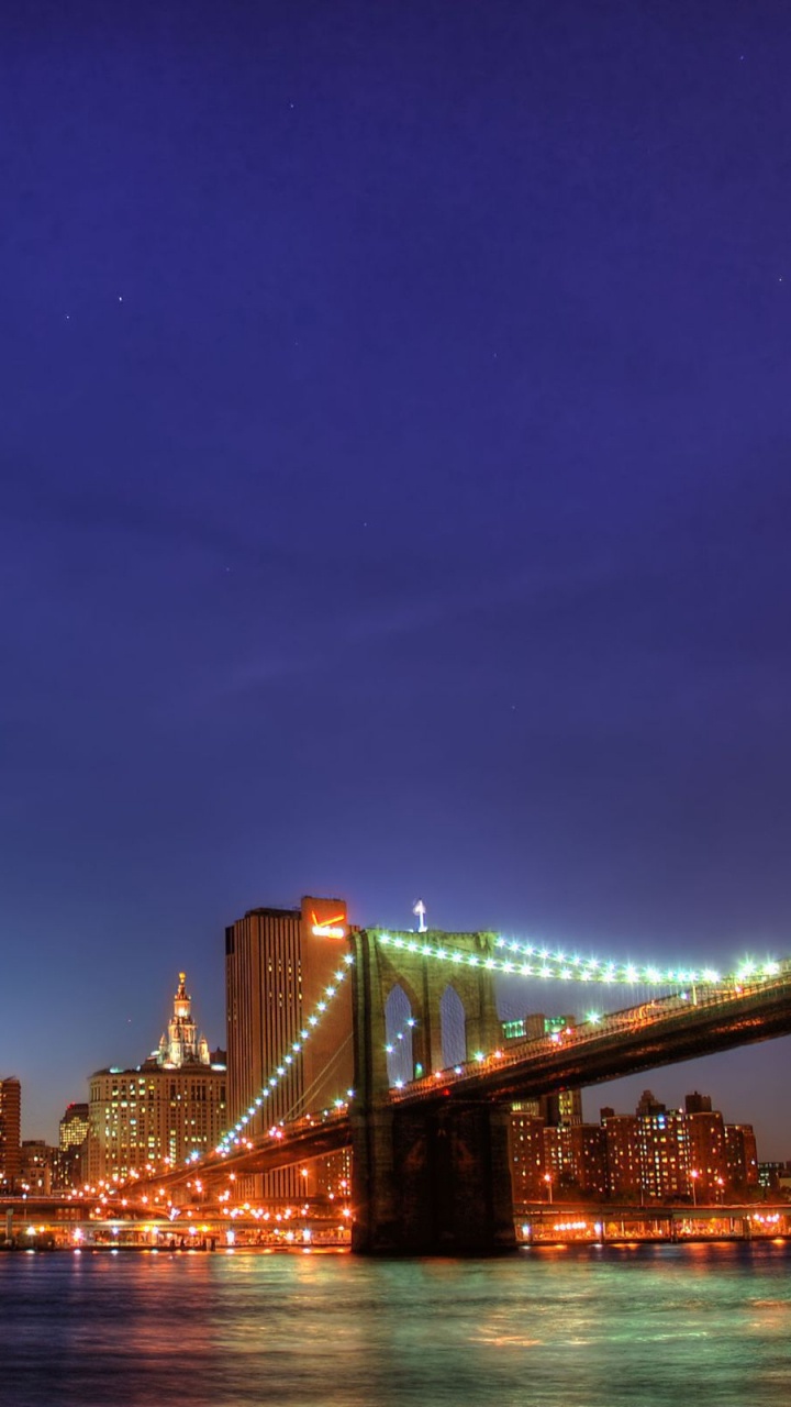 Lighted Bridge Over Water During Night Time. Wallpaper in 720x1280 Resolution