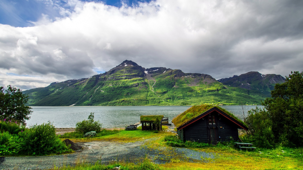 Brown Wooden House on Green Grass Field Near Lake Under White Clouds and Blue Sky During. Wallpaper in 1280x720 Resolution