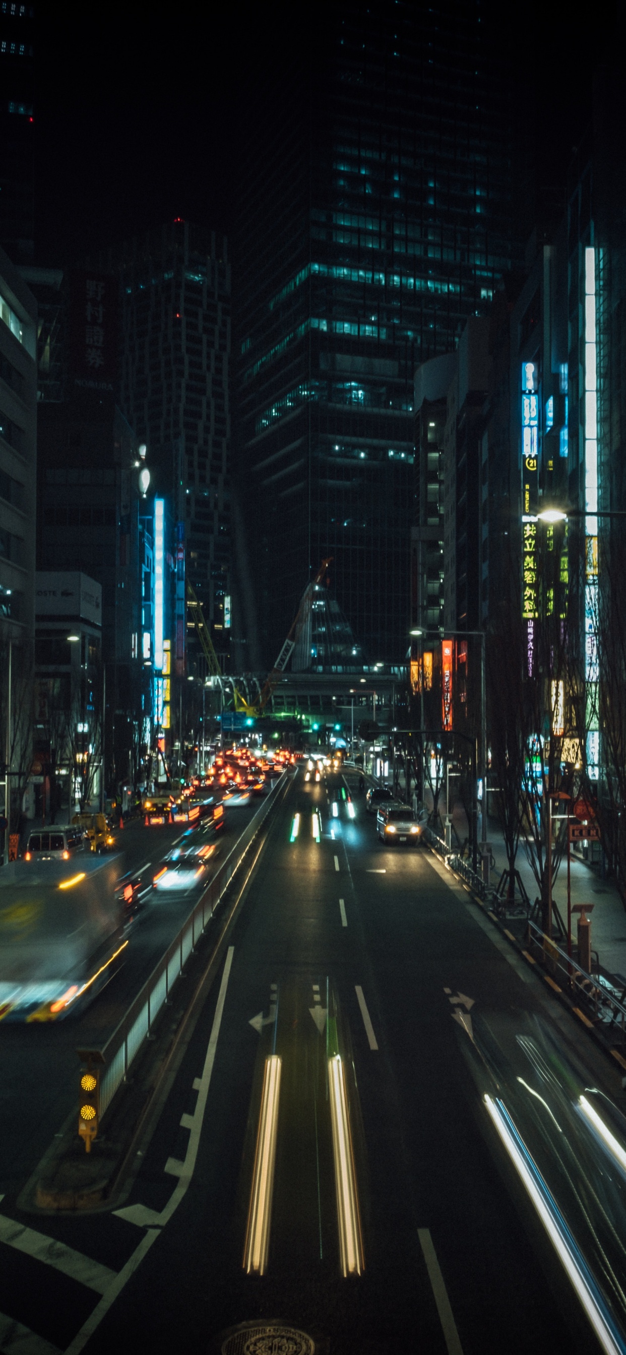 Autos Auf Der Straße Zwischen Hochhäusern Während Der Nacht. Wallpaper in 1242x2688 Resolution