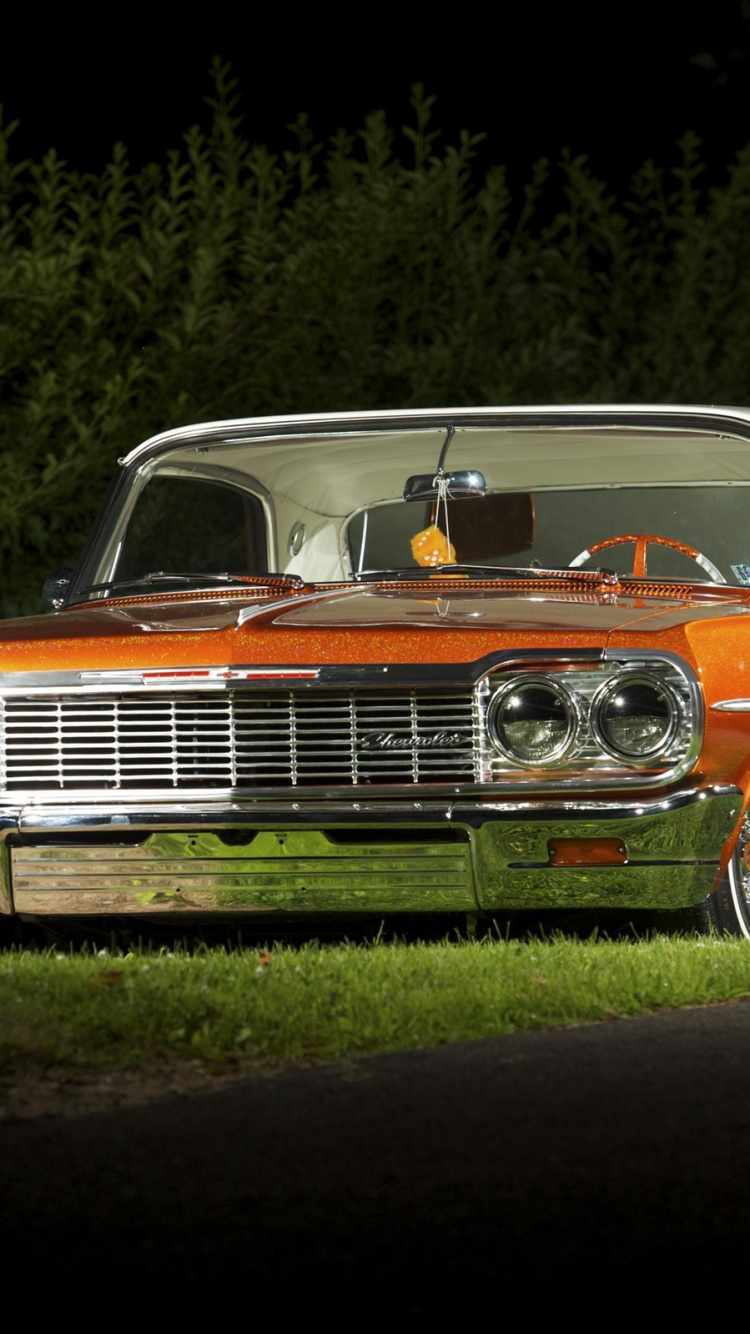 Coche Chevrolet Naranja Estacionado en el Campo de Hierba Verde Durante el Día. Wallpaper in 750x1334 Resolution