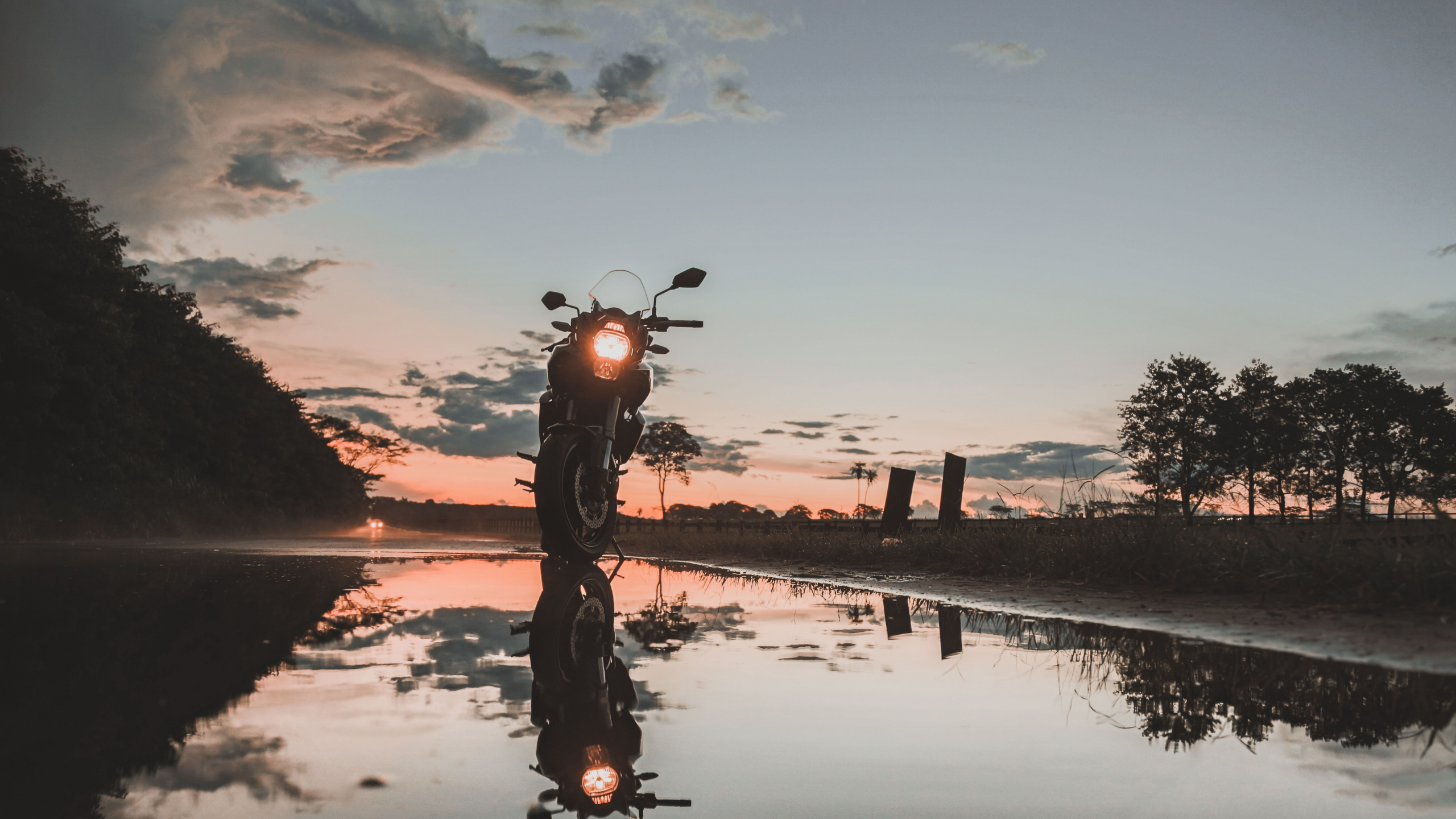 Mann, Der Während Des Sonnenuntergangs Fahrrad Auf Dem See Fährt. Wallpaper in 2560x1440 Resolution