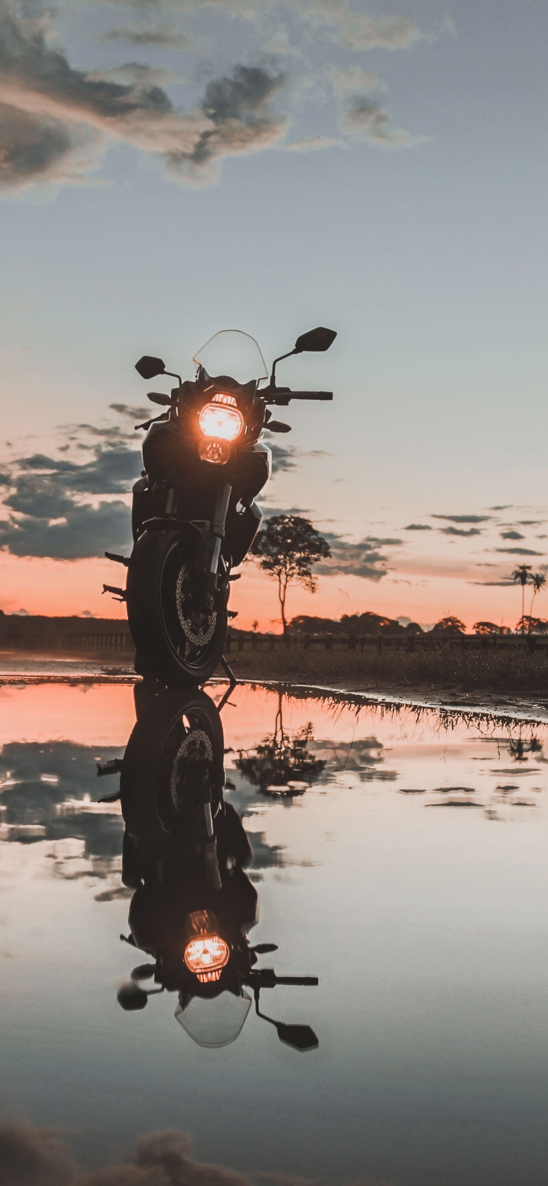 Hombre Montando Bicicleta en el Lago Durante la Puesta de Sol. Wallpaper in 1125x2436 Resolution