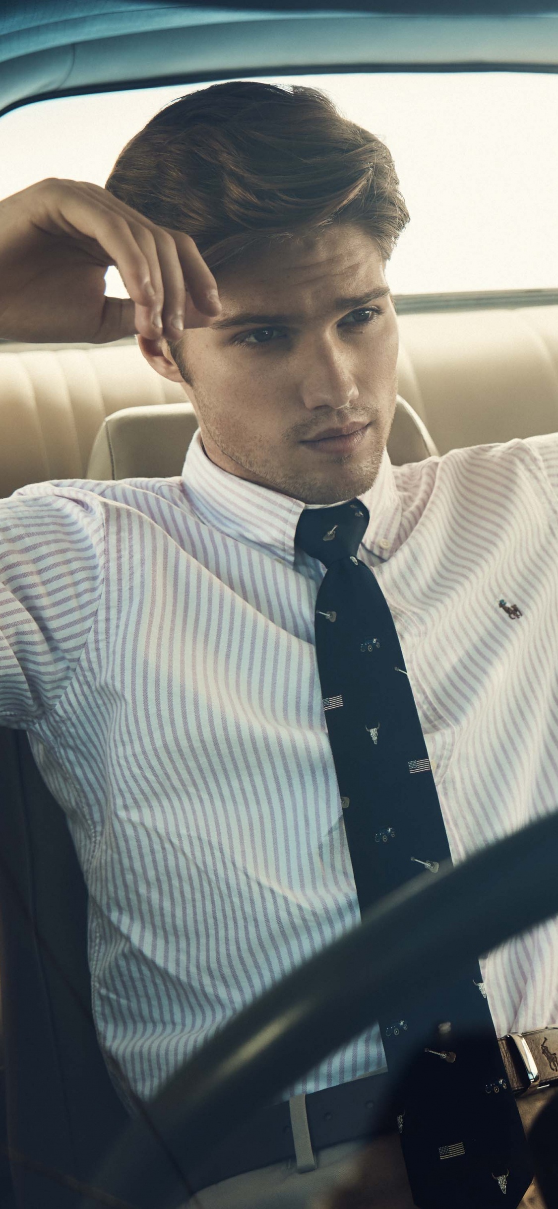 Man in White and Black Striped Long Sleeve Shirt Driving Car. Wallpaper in 1125x2436 Resolution