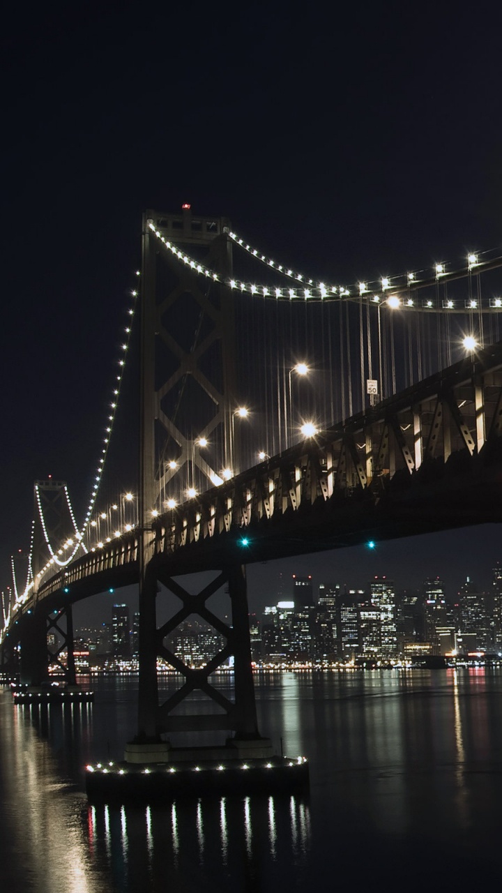 Puente Iluminado Sobre el Cuerpo de Agua Durante la Noche. Wallpaper in 720x1280 Resolution