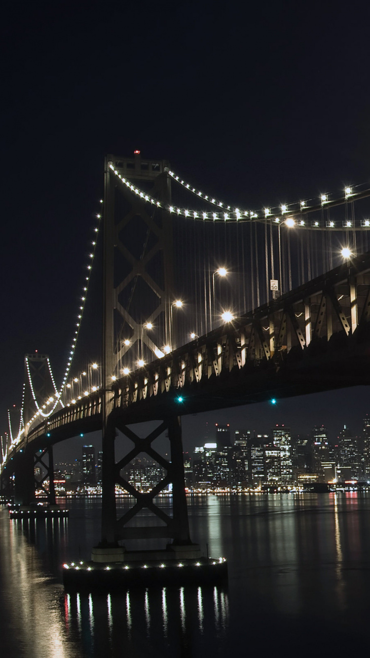 Puente Iluminado Sobre el Cuerpo de Agua Durante la Noche. Wallpaper in 750x1334 Resolution