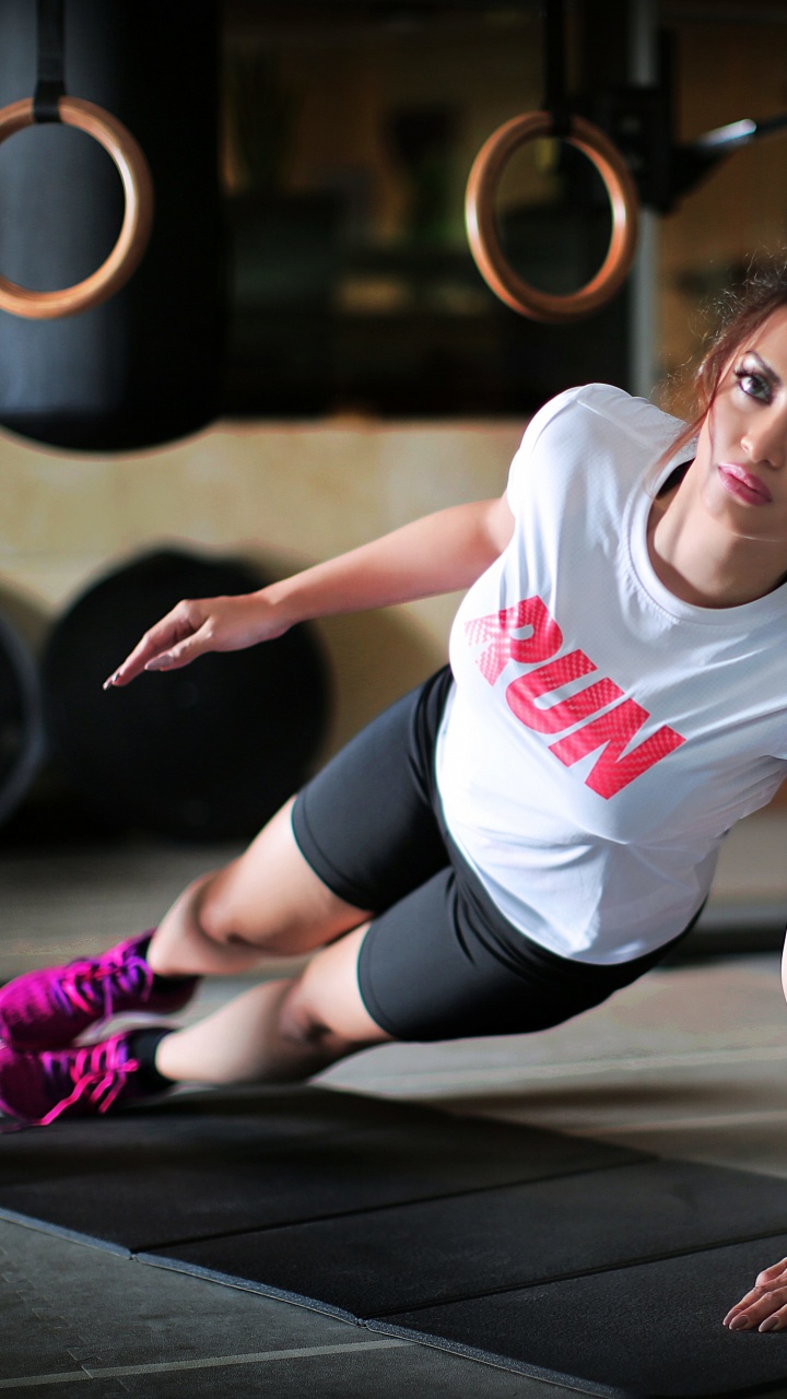 Mujer en Camiseta Blanca Con Cuello Redondo y Pantalones Cortos Negros Sentada Sobre un Piso de Madera Negra. Wallpaper in 720x1280 Resolution