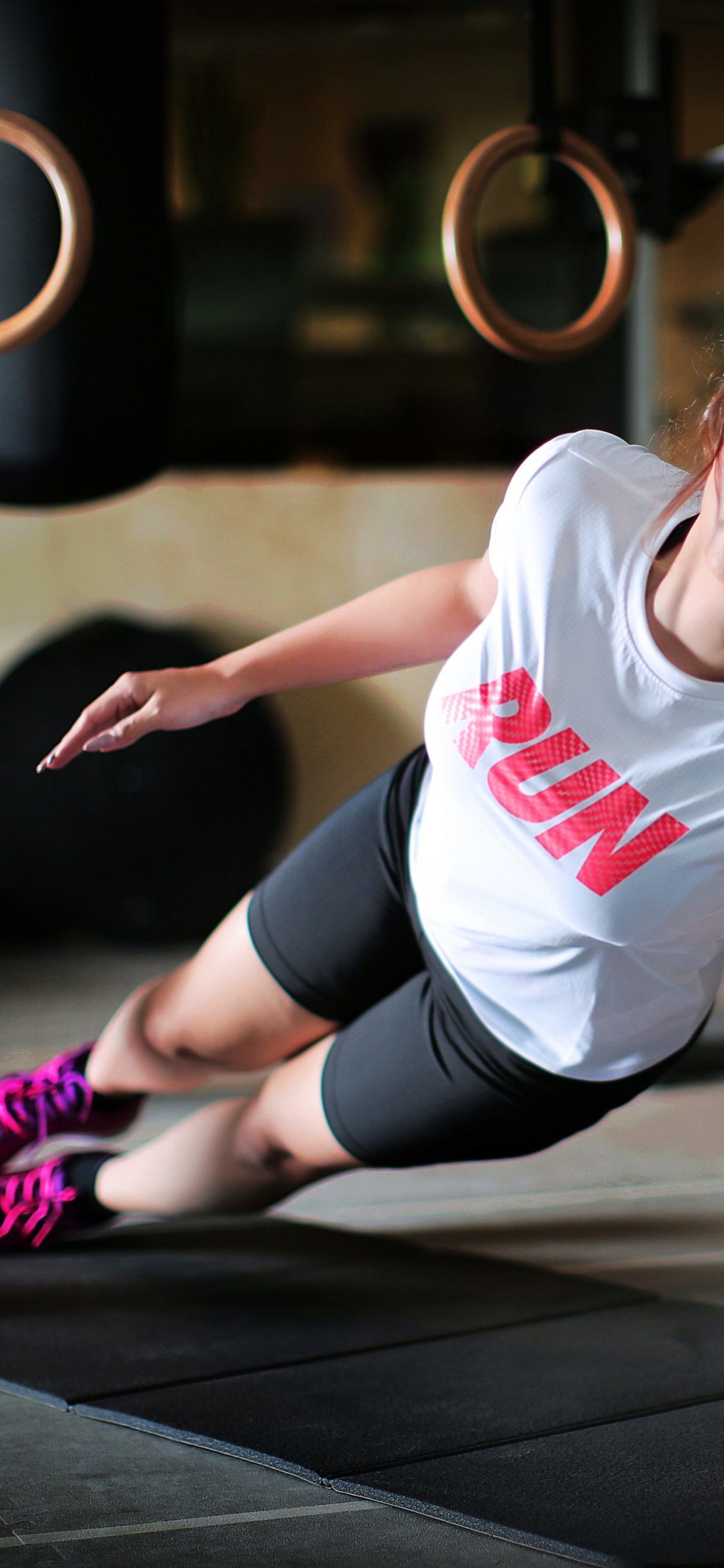 Woman in White Crew Neck T-shirt and Black Shorts Sitting on Black Wooden Floor. Wallpaper in 1242x2688 Resolution