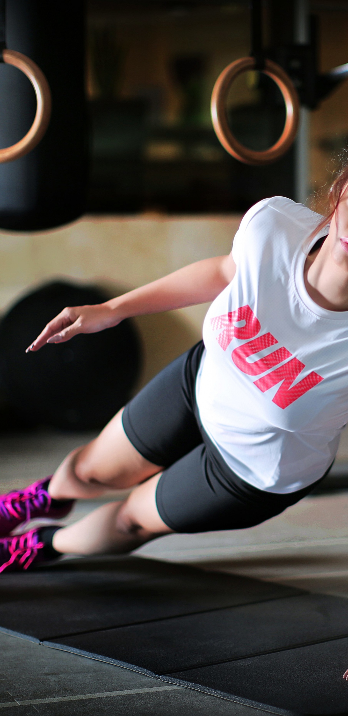 Woman in White Crew Neck T-shirt and Black Shorts Sitting on Black Wooden Floor. Wallpaper in 1440x2960 Resolution