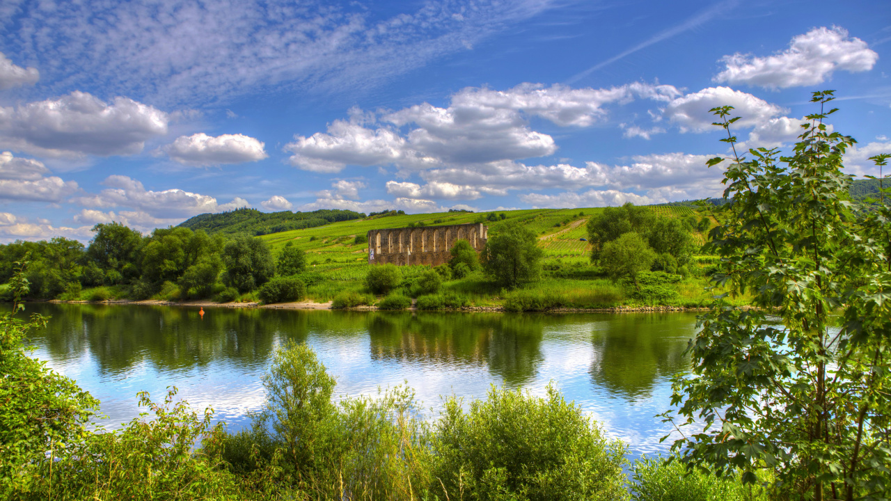 Grüne Wiese in Der Nähe Des Sees Unter Blauem Himmel Tagsüber. Wallpaper in 1280x720 Resolution